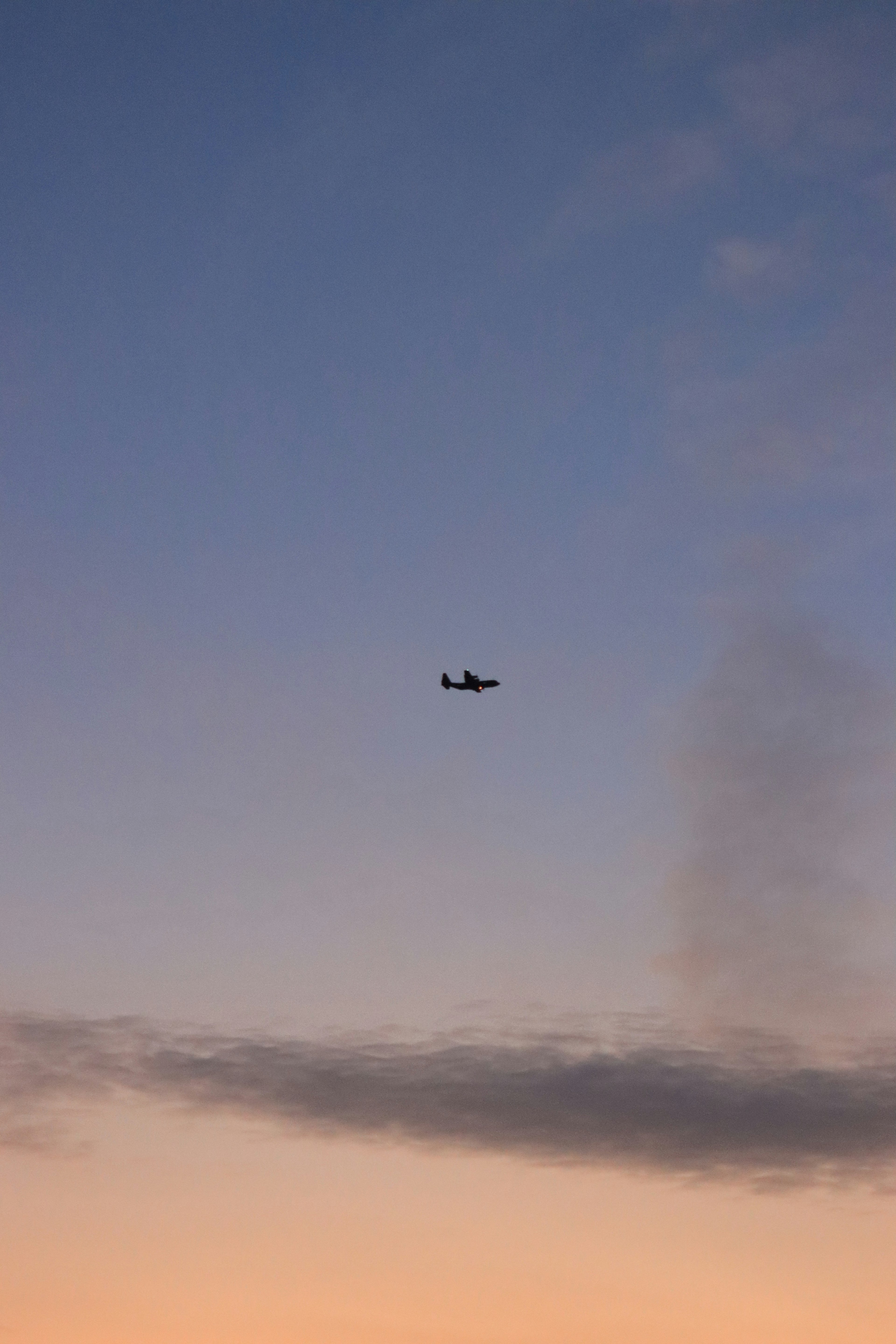 Kleines Flugzeug fliegt am Himmel während des Sonnenuntergangs mit Wolken