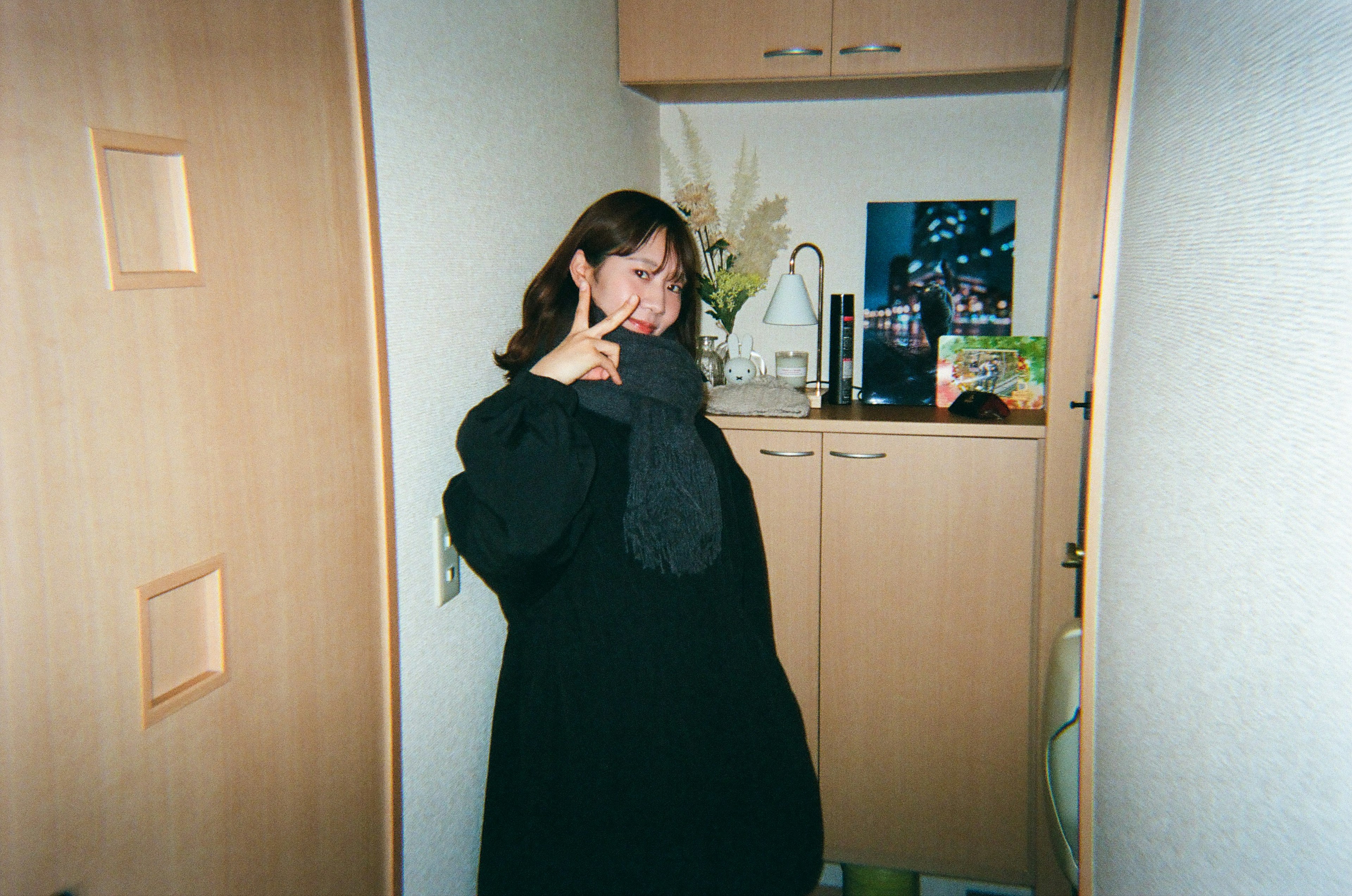 A woman in a black coat posing with a peace sign at the kitchen entrance