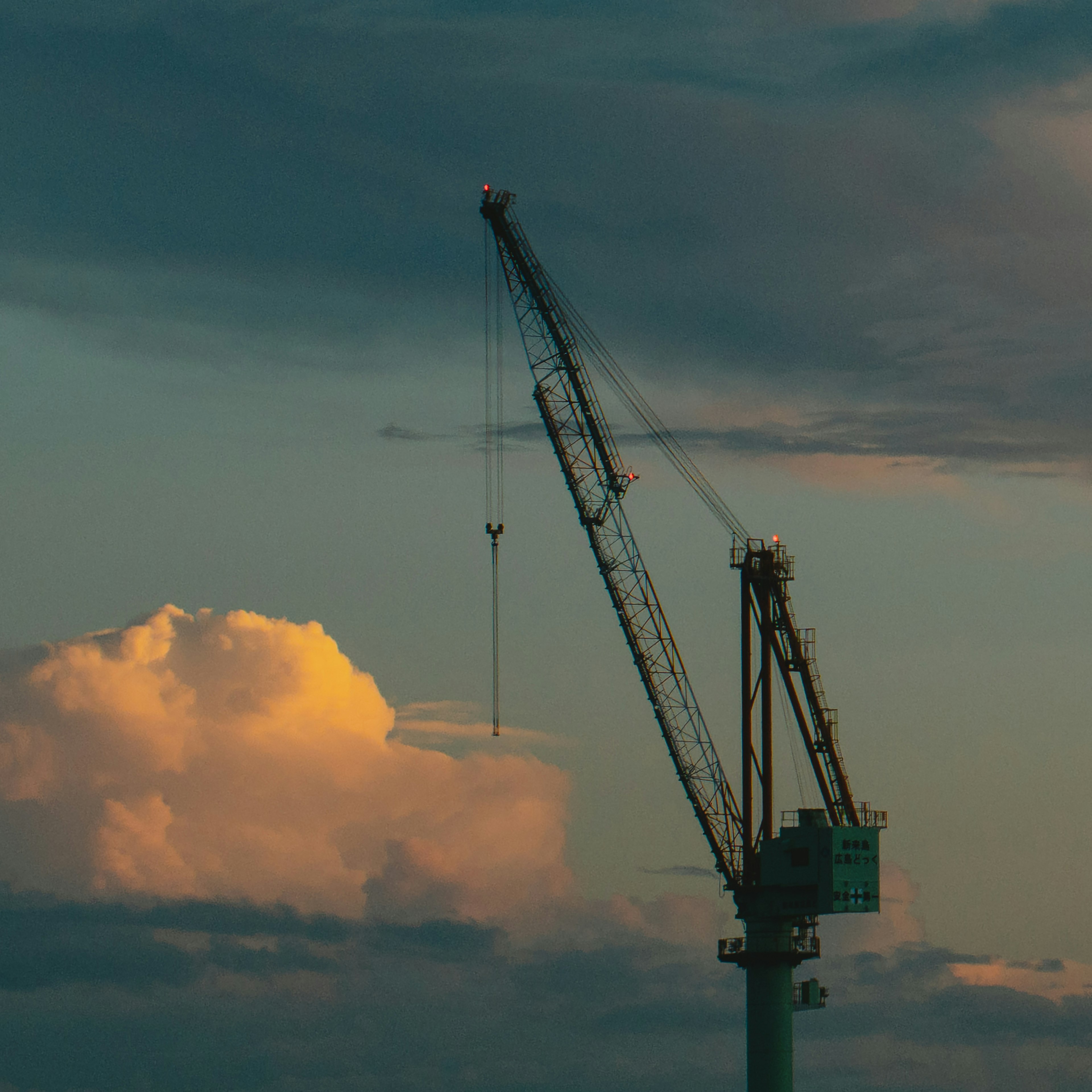 夕焼けの空に立つクレーンと雲