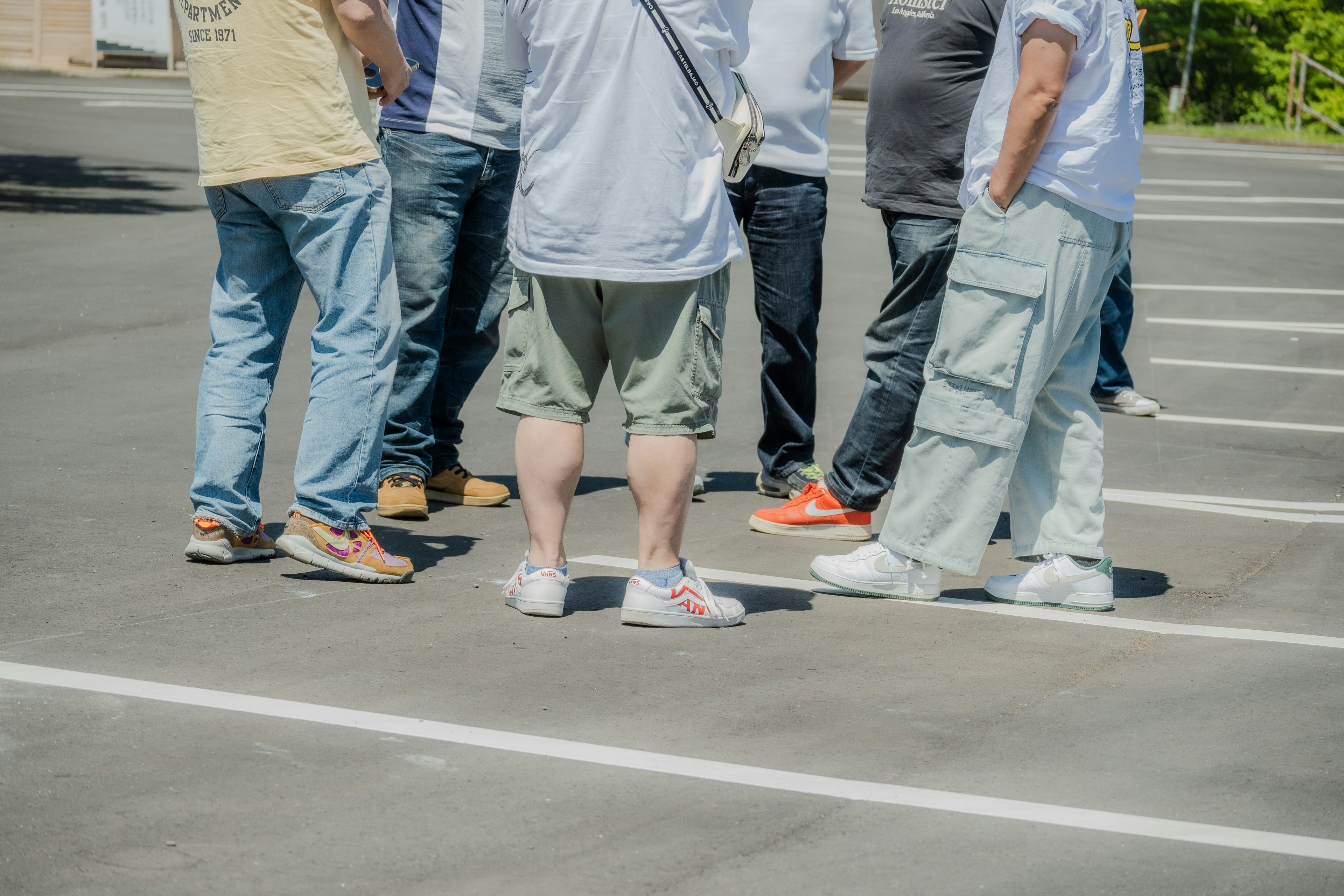 Un grupo de varias personas reunidas en un estacionamiento conversando