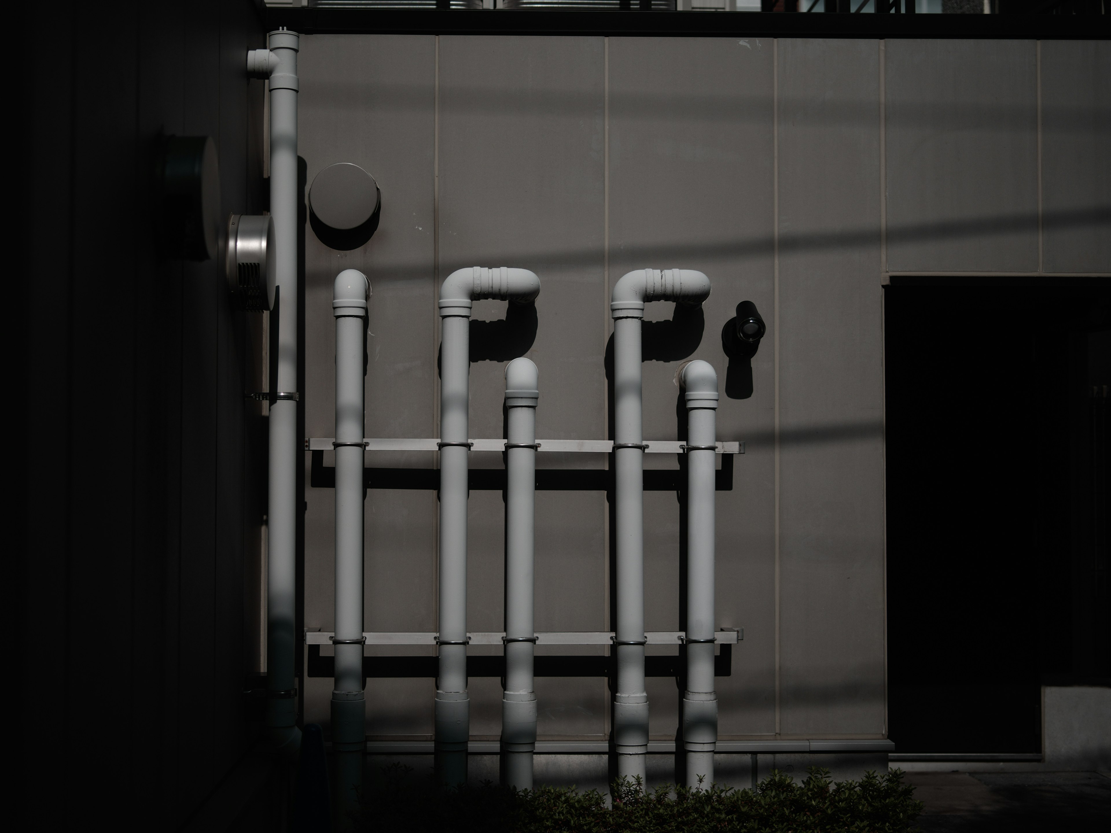 Des tuyaux blancs montés sur un mur dans une structure simple