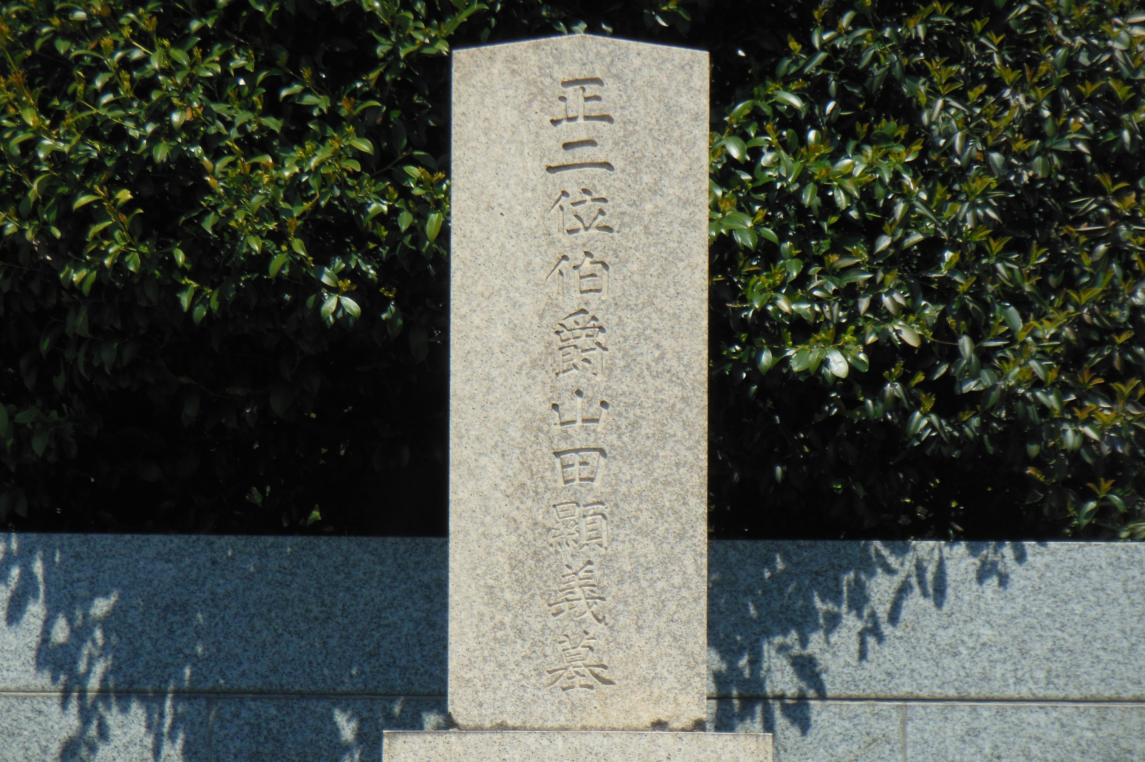 Monumento de piedra con texto grabado y fondo de follaje verde