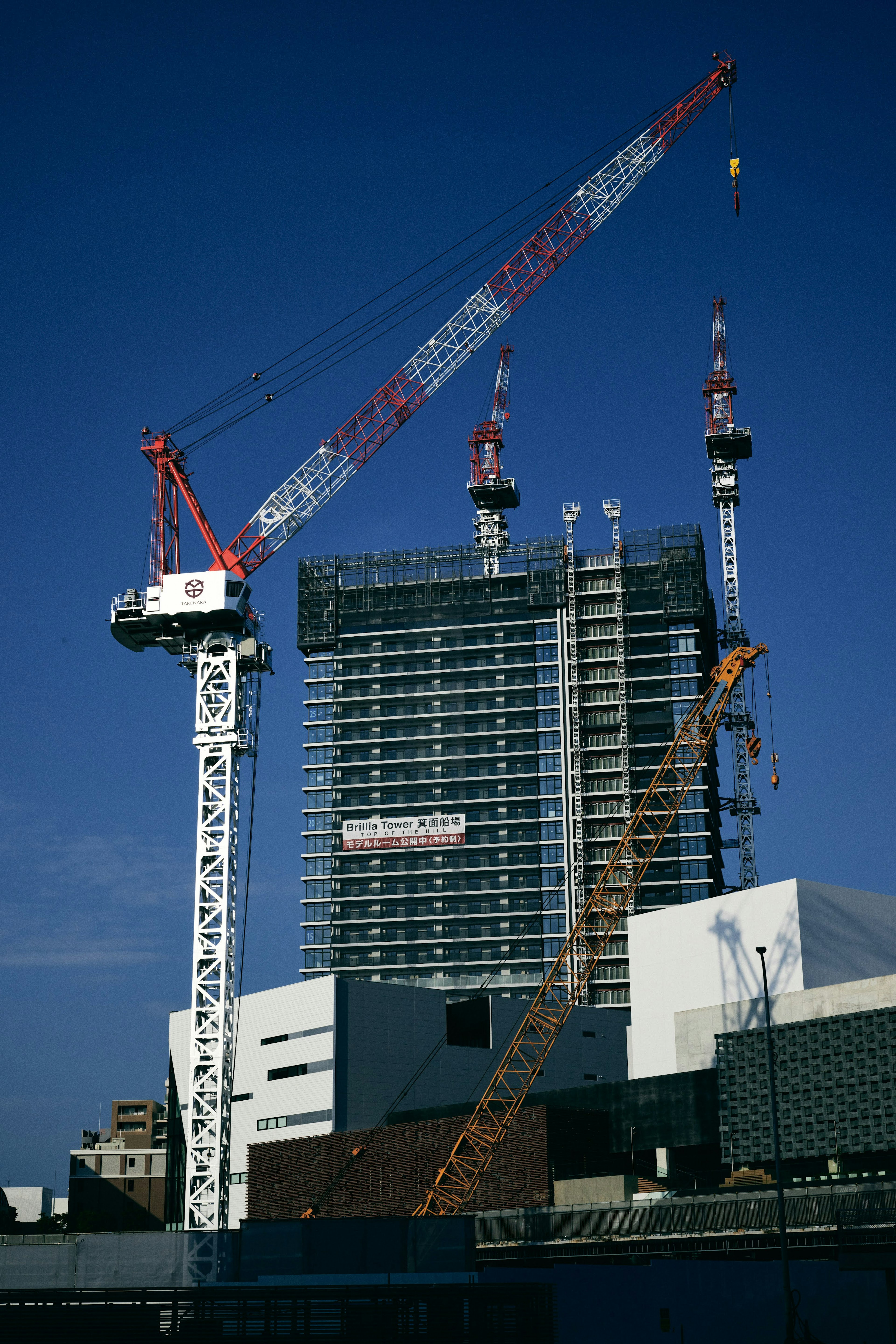 Site de construction avec plusieurs grues et un immeuble de grande hauteur