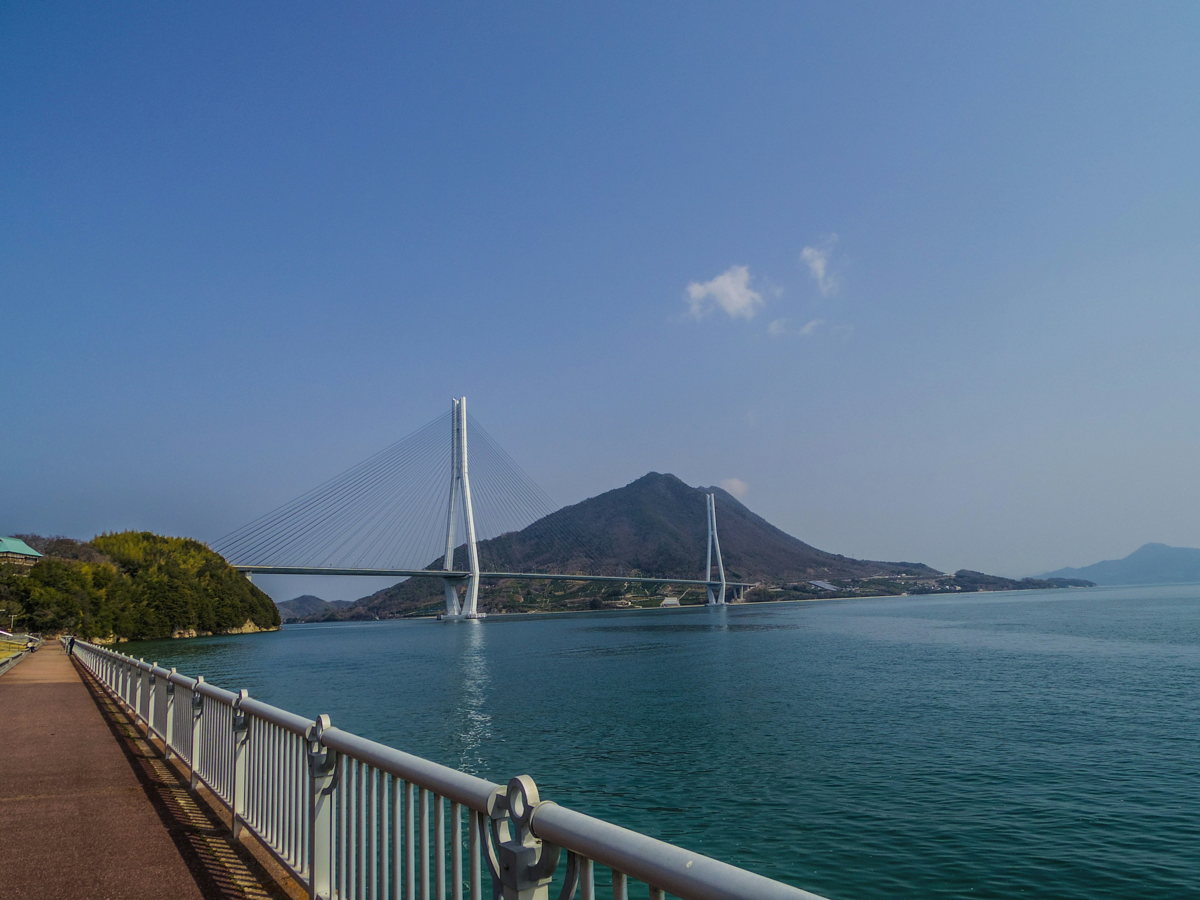 Malersicher Blick auf eine Brücke über blaues Wasser mit Bergen im Hintergrund