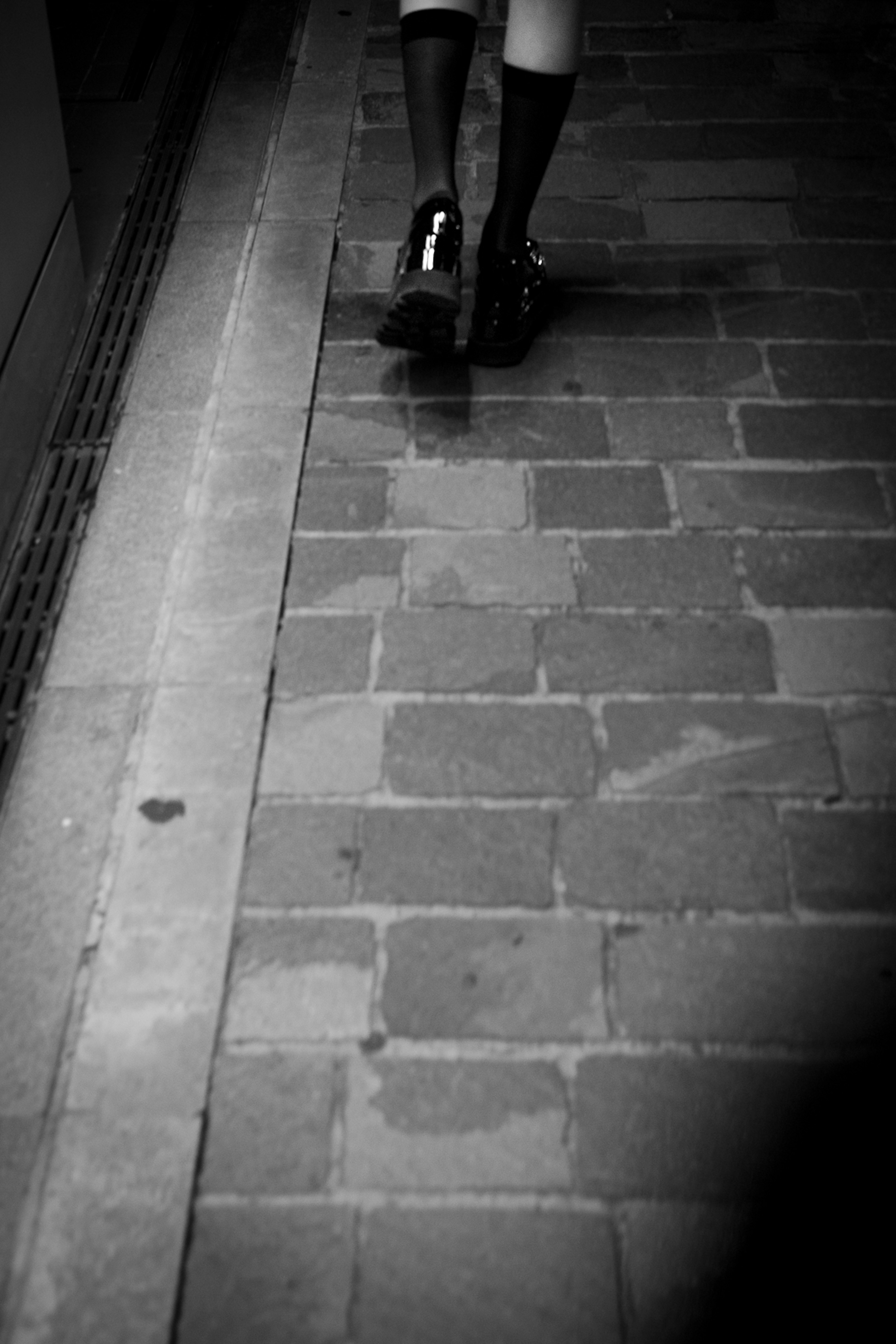 Person's feet wearing black and white striped socks walking on cobblestone path