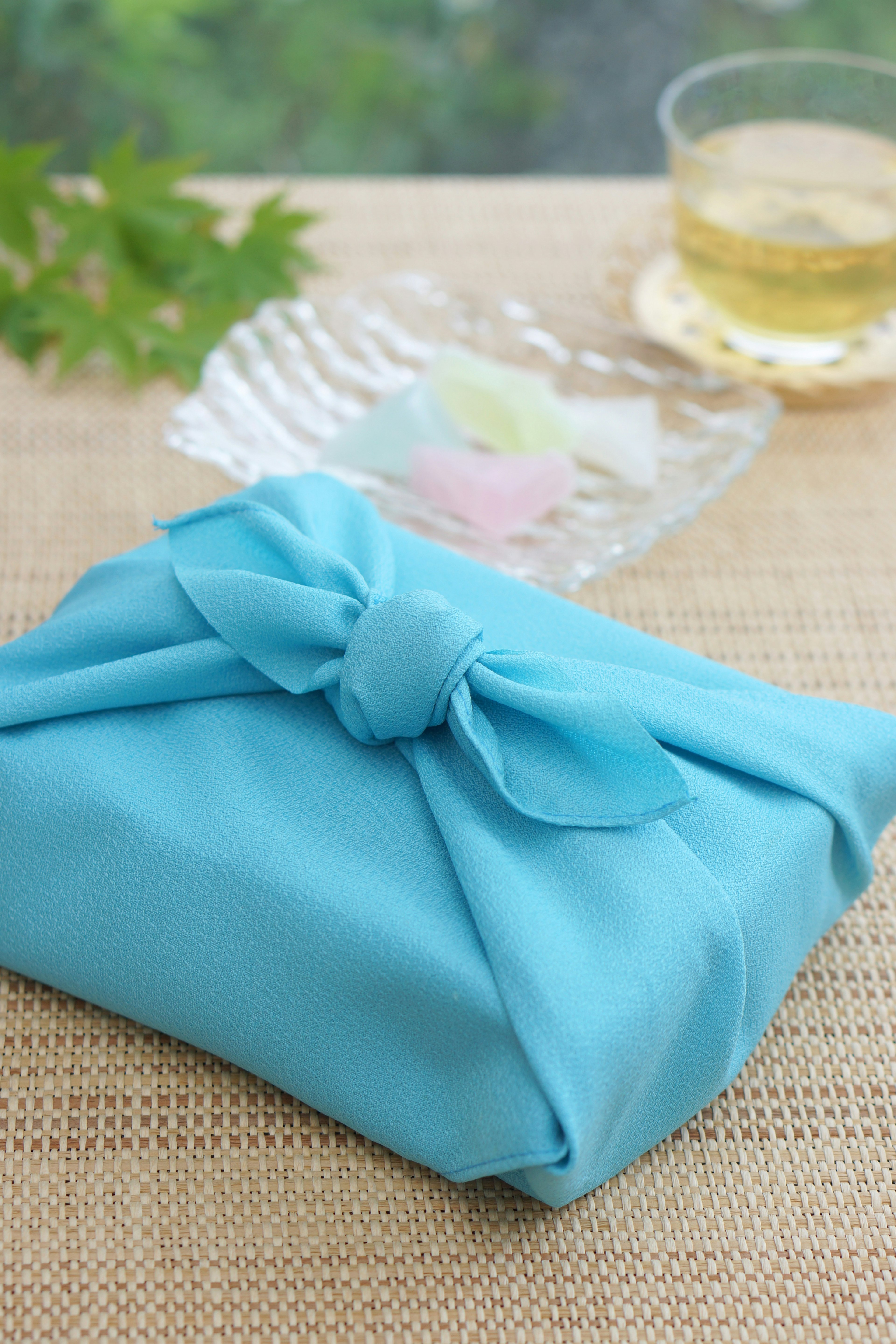 A blue cloth-wrapped gift with green leaves and a glass of tea