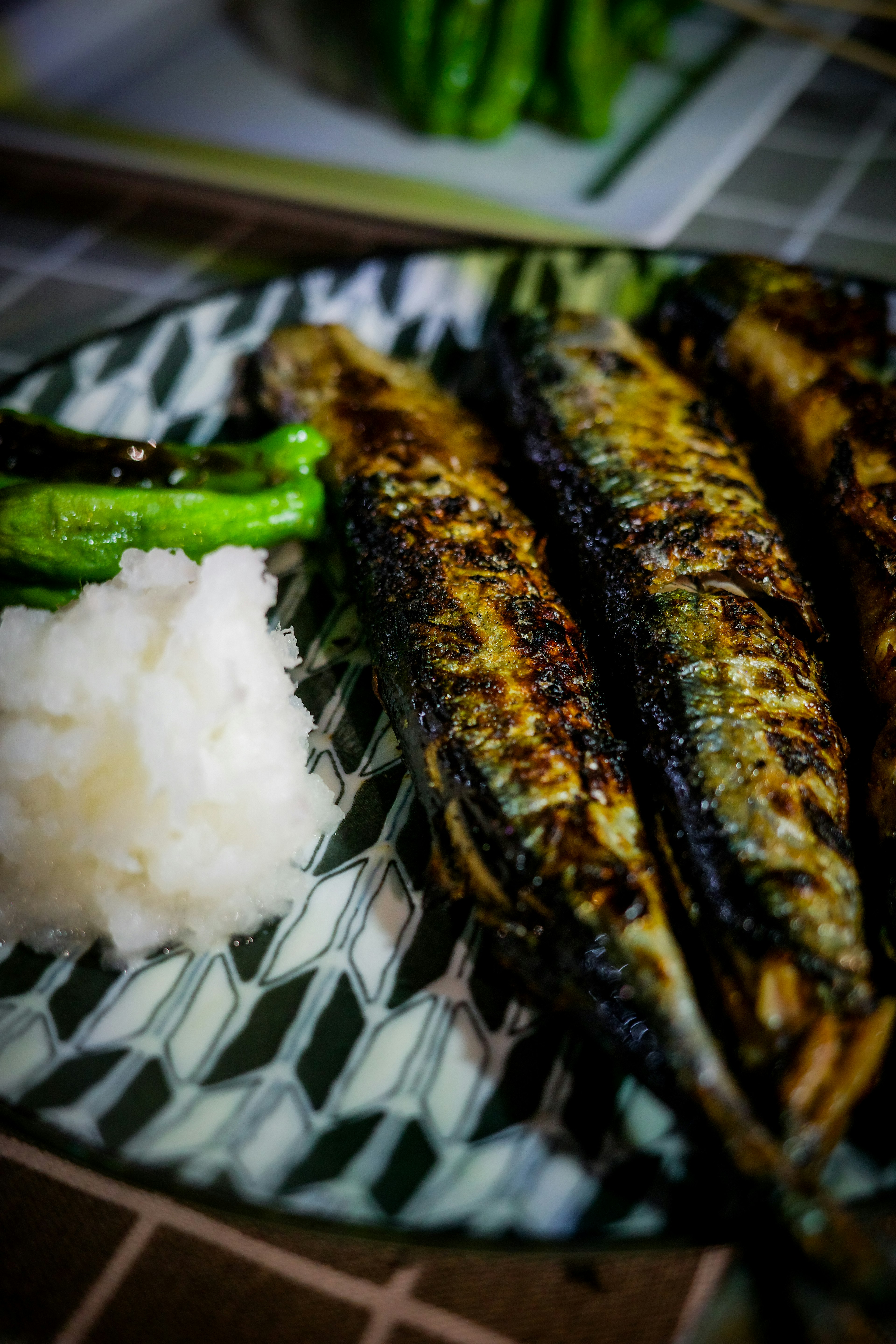 Poisson sanma grillé servi avec du radis râpé et des poivrons verts