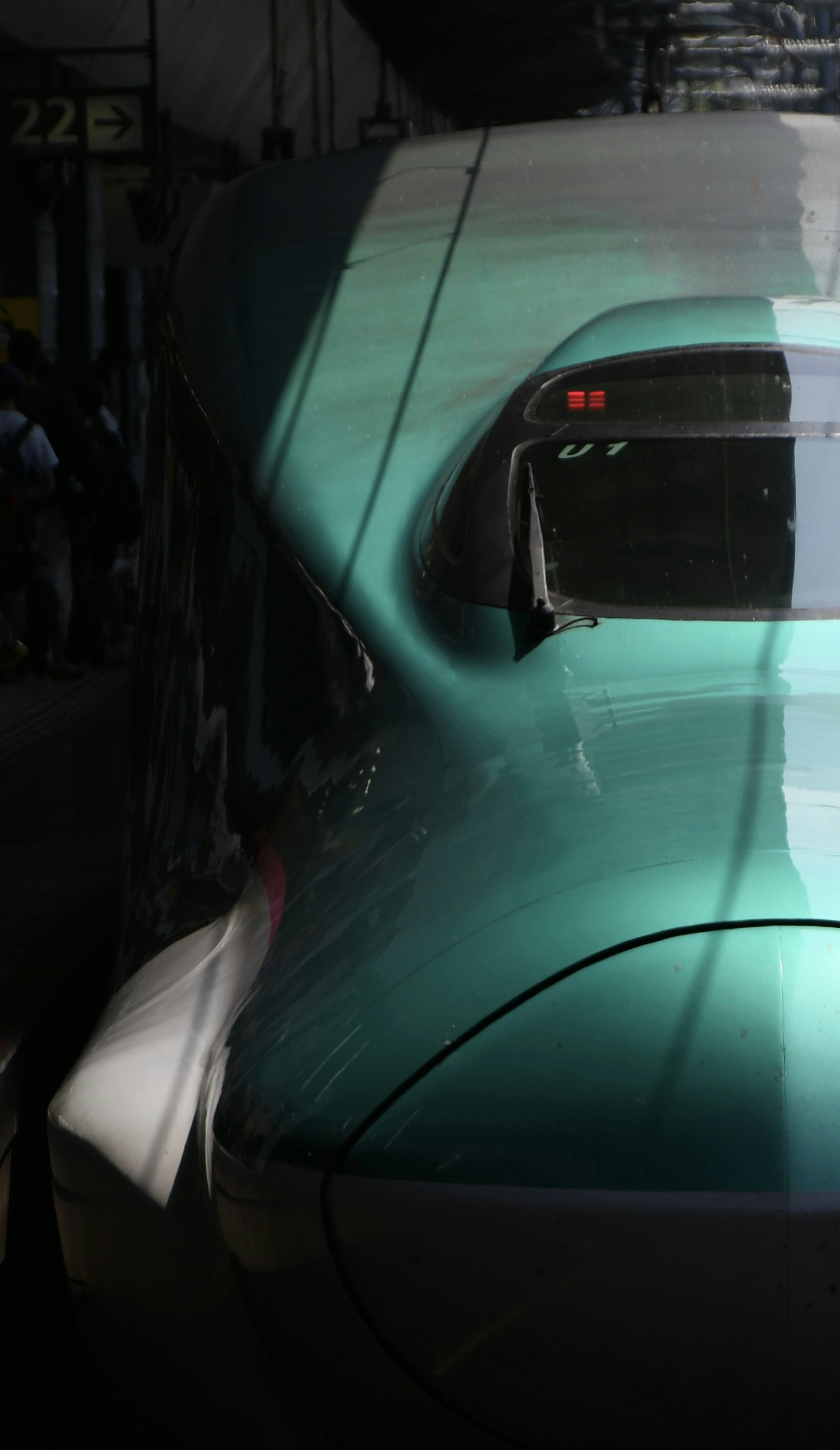 Rear view of a green Shinkansen train with a dark background