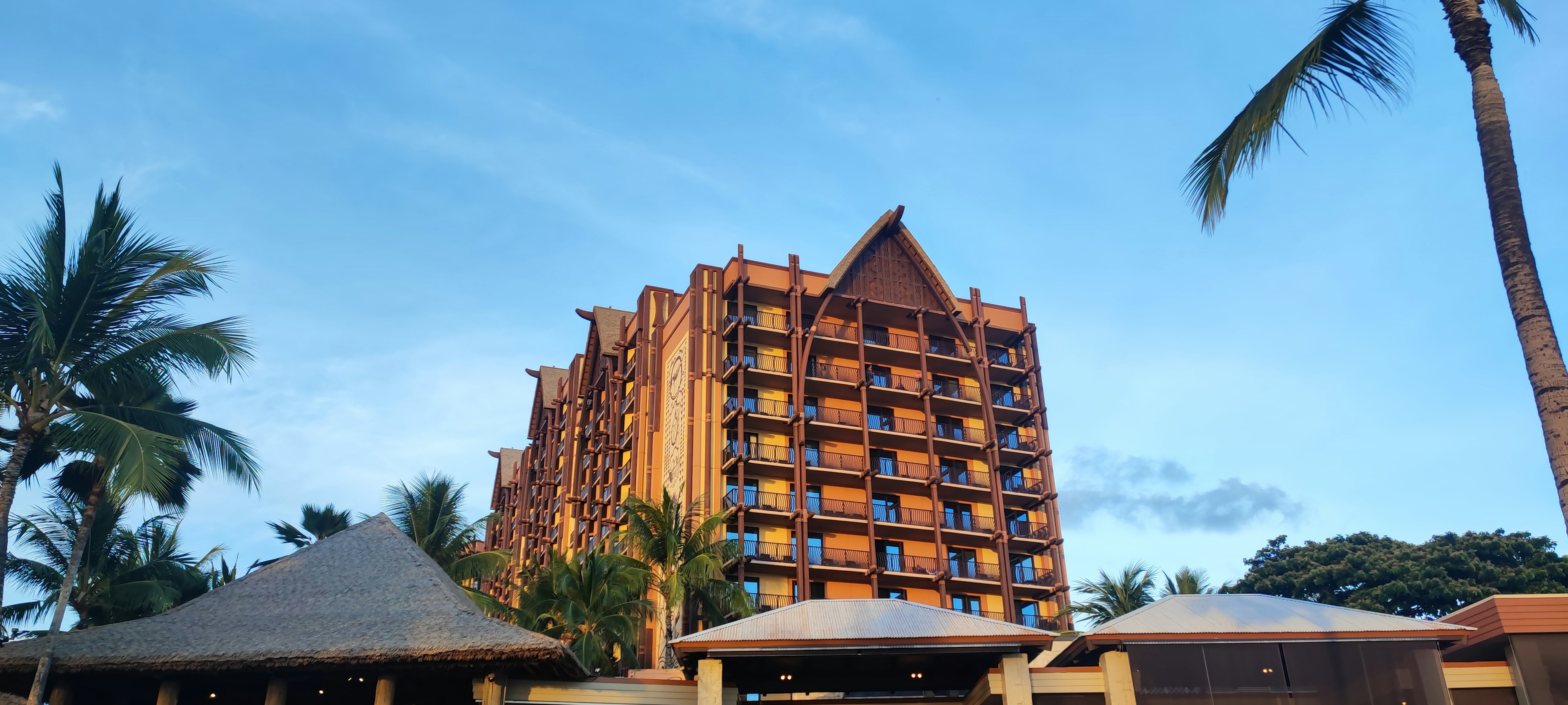 Hôtel de villégiature orange sous un ciel bleu avec des palmiers