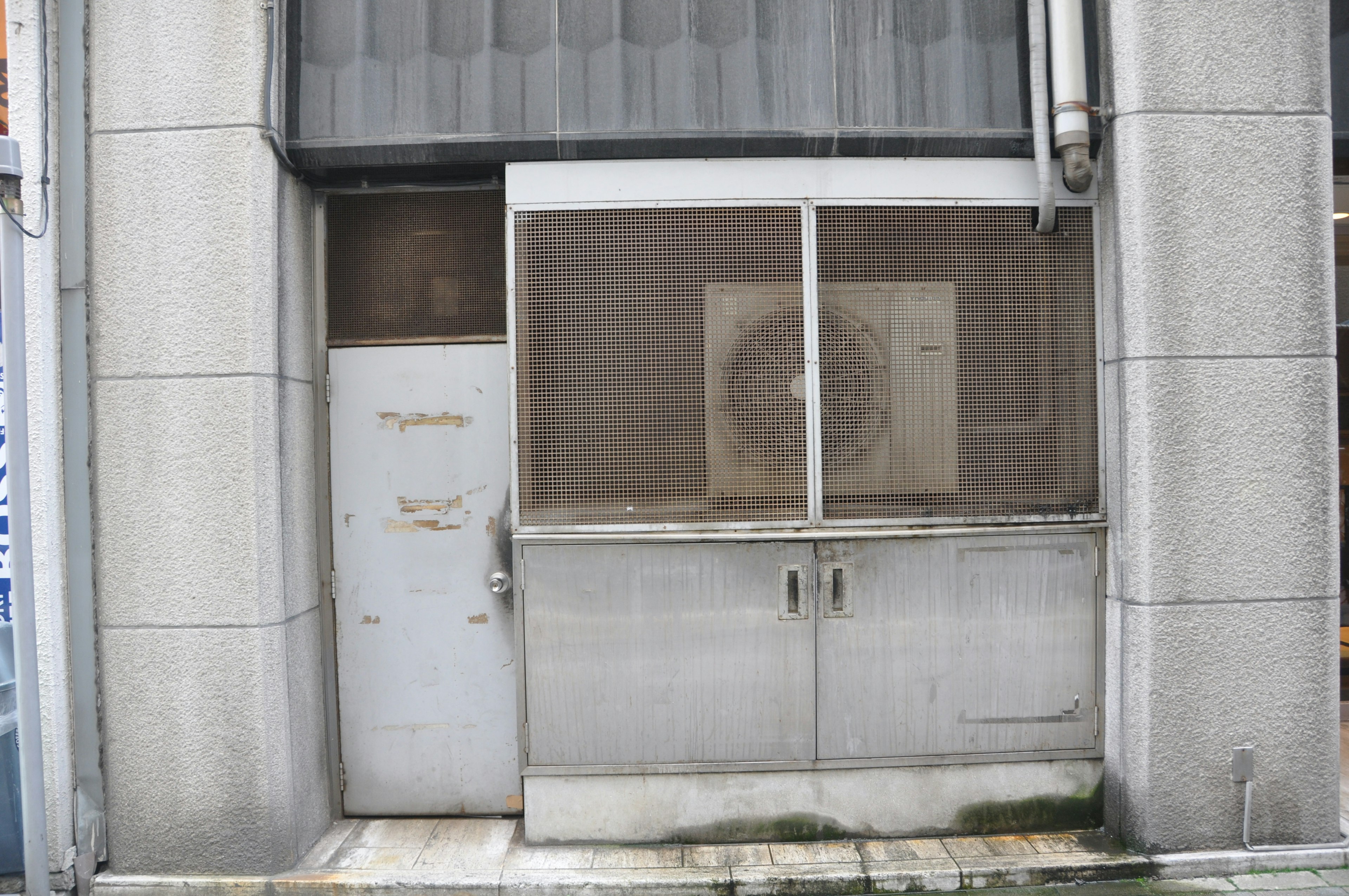 Extérieur d'un bâtiment avec une vieille porte en métal et une fenêtre