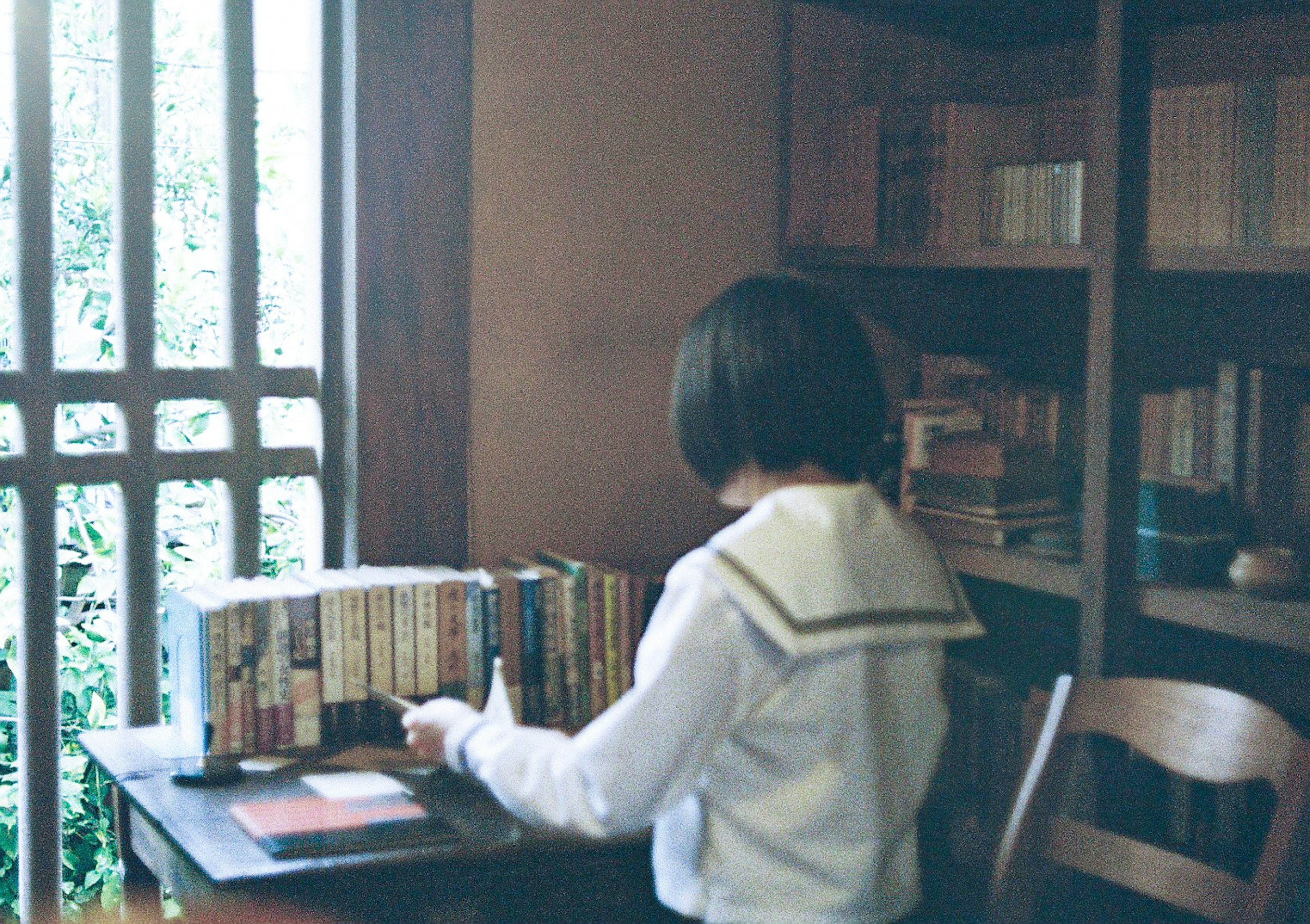 A student organizing books in front of a bookshelf