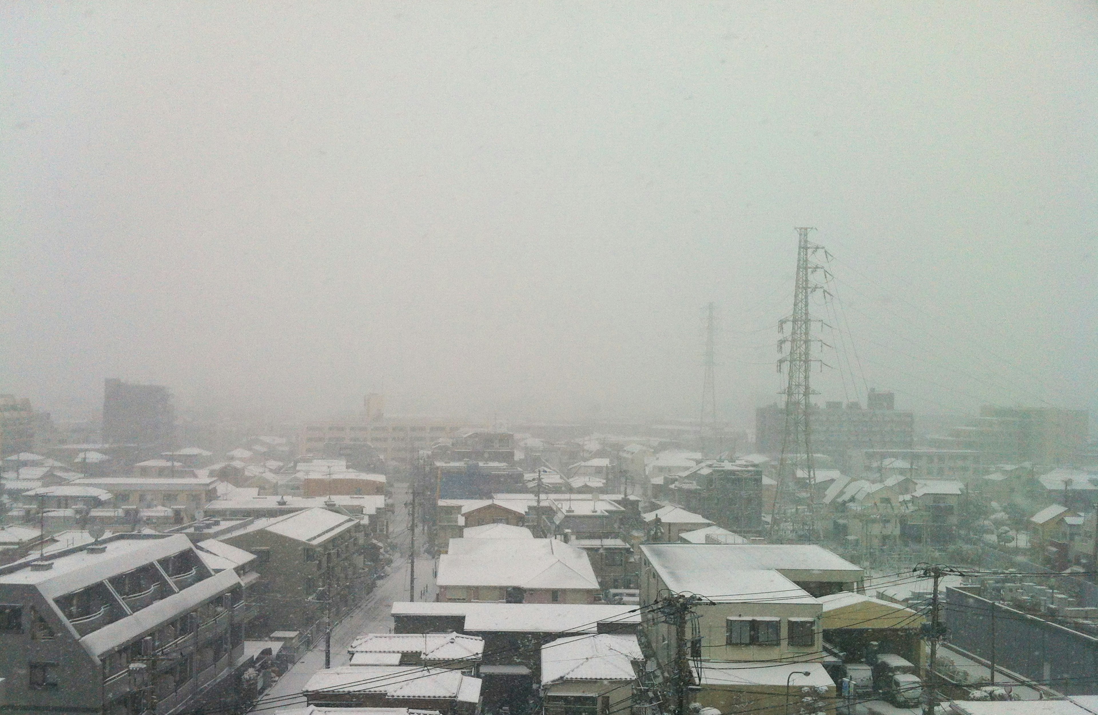 雪天的城市景观，建筑被雪覆盖，雾气弥漫