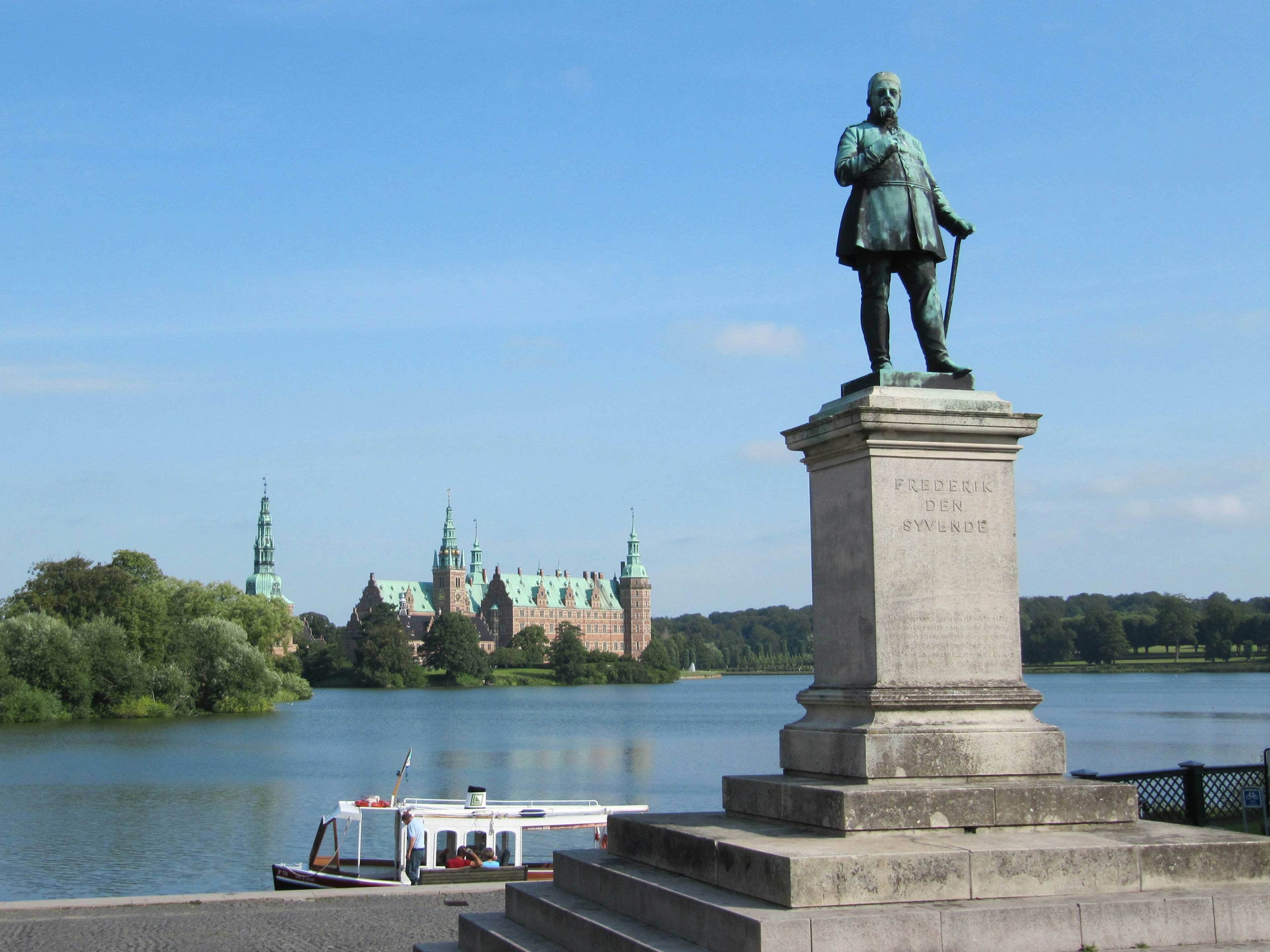 Estatua de bronce bajo un cielo azul con castillo al fondo