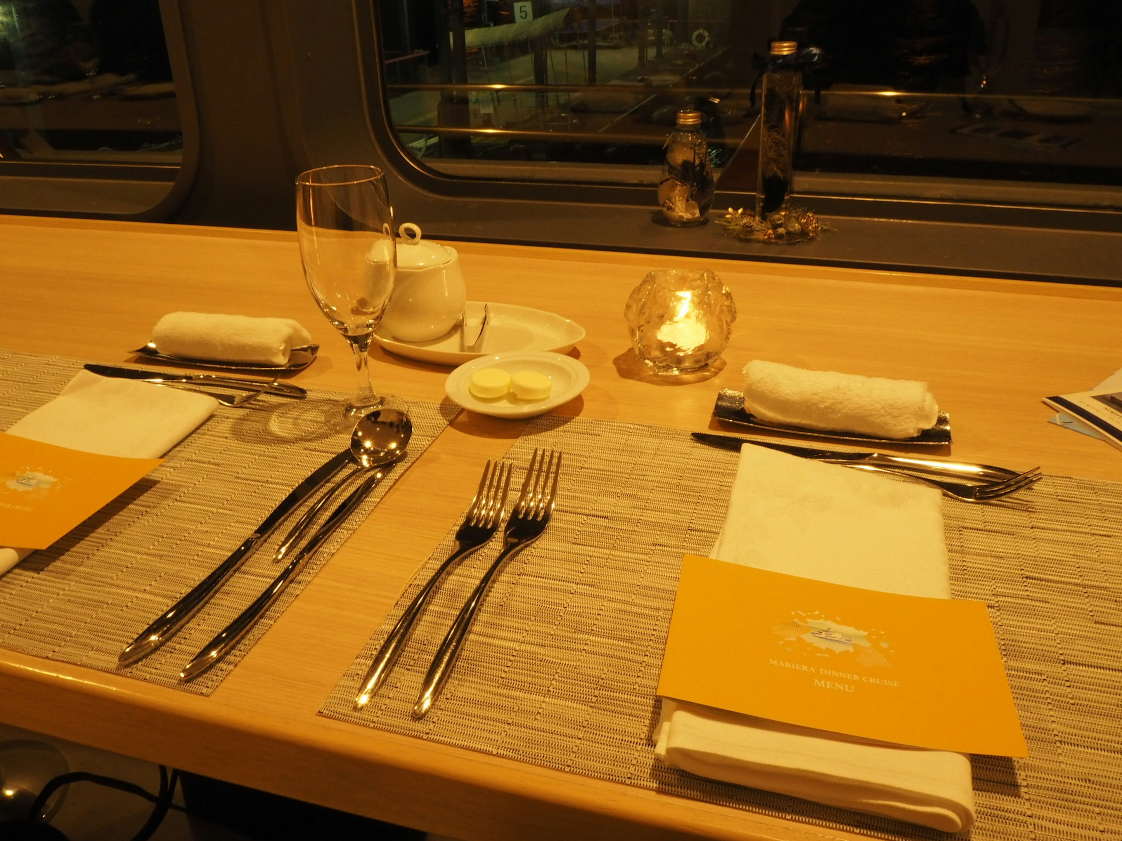 Table de dîner dressée avec des ustensiles et des menus dans une ambiance chaleureuse