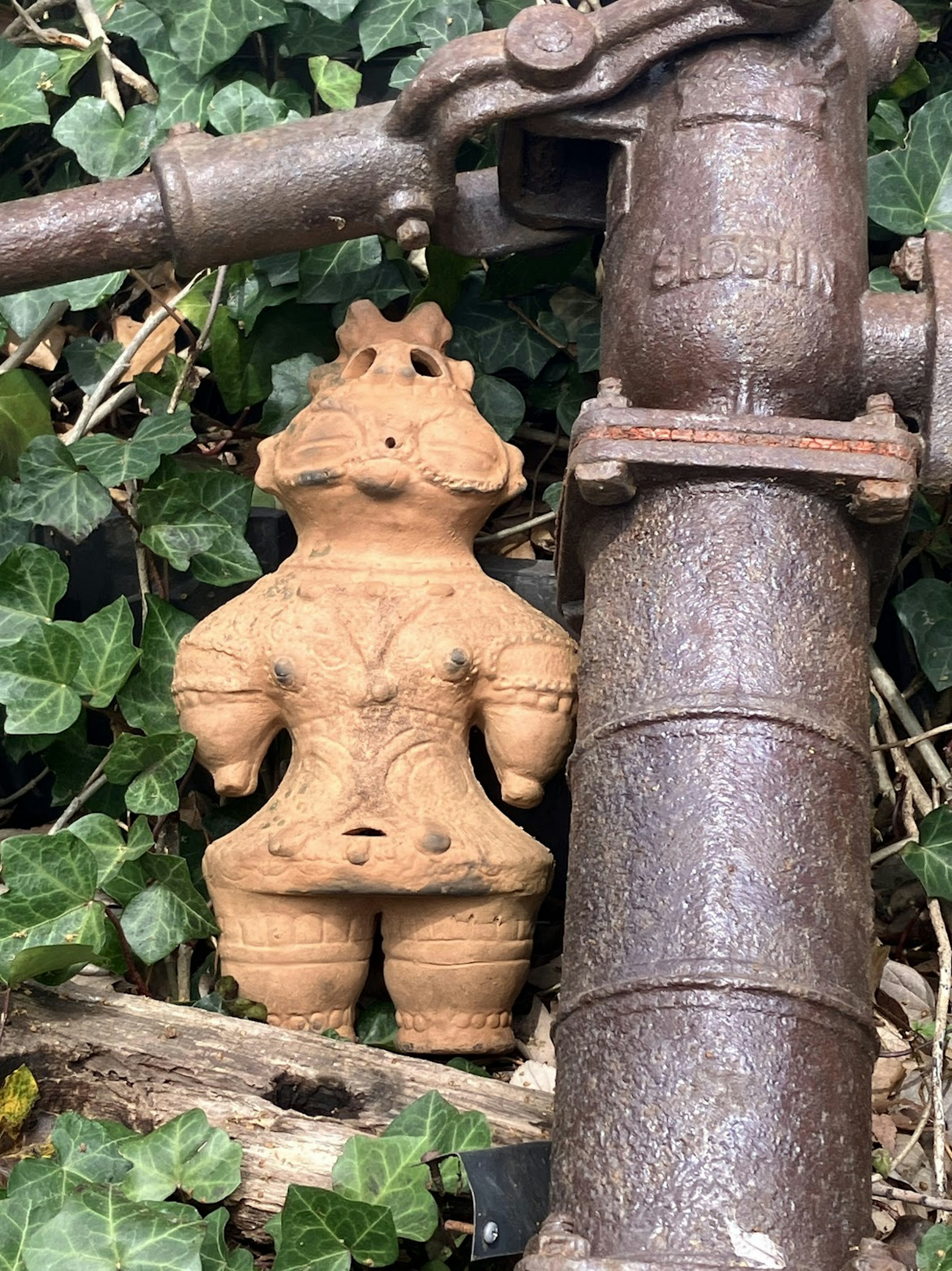 Figurita de cerámica colocada junto a una vieja bomba de agua