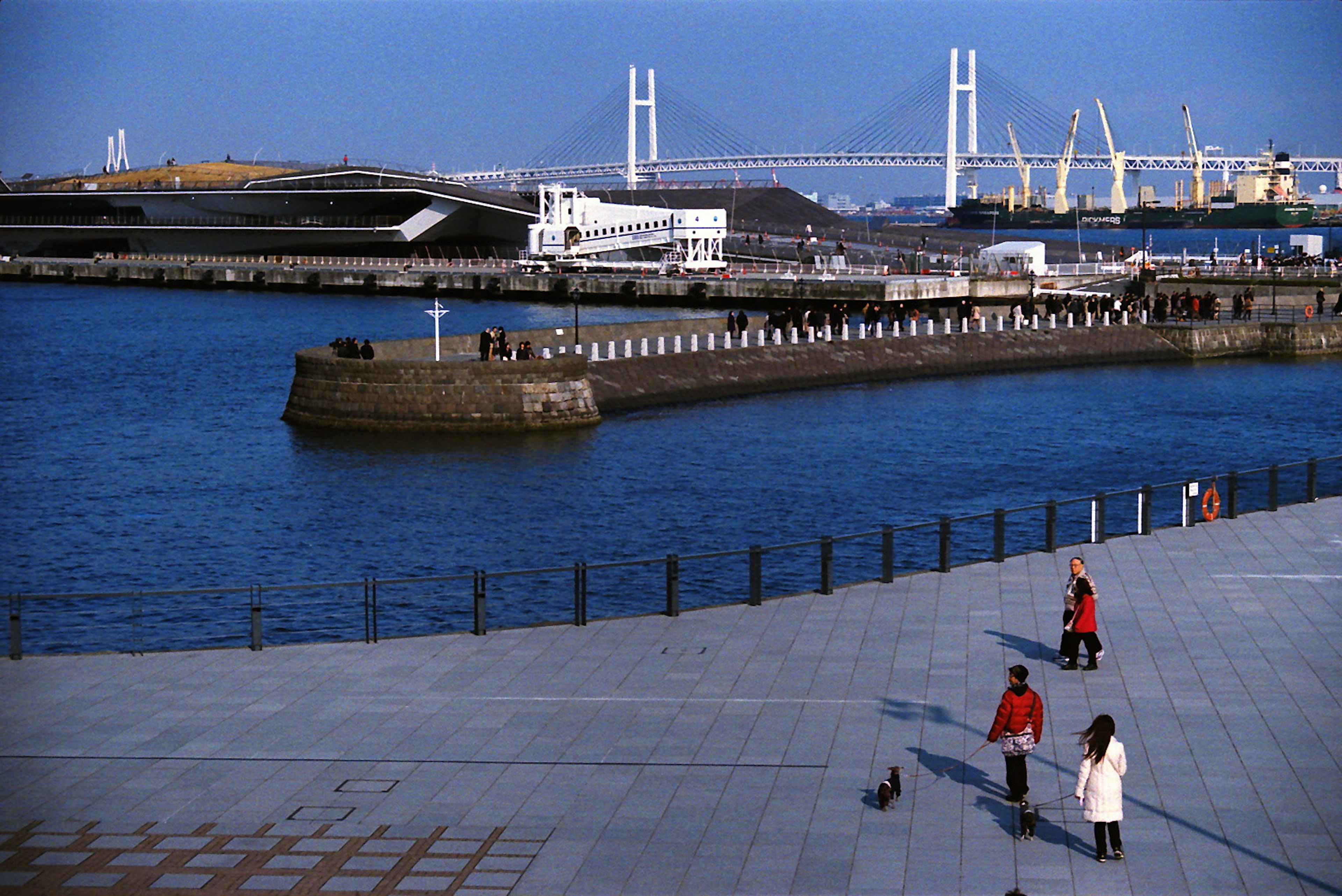 Menschen, die am Hafen entlanggehen mit blauem Meer und Himmel