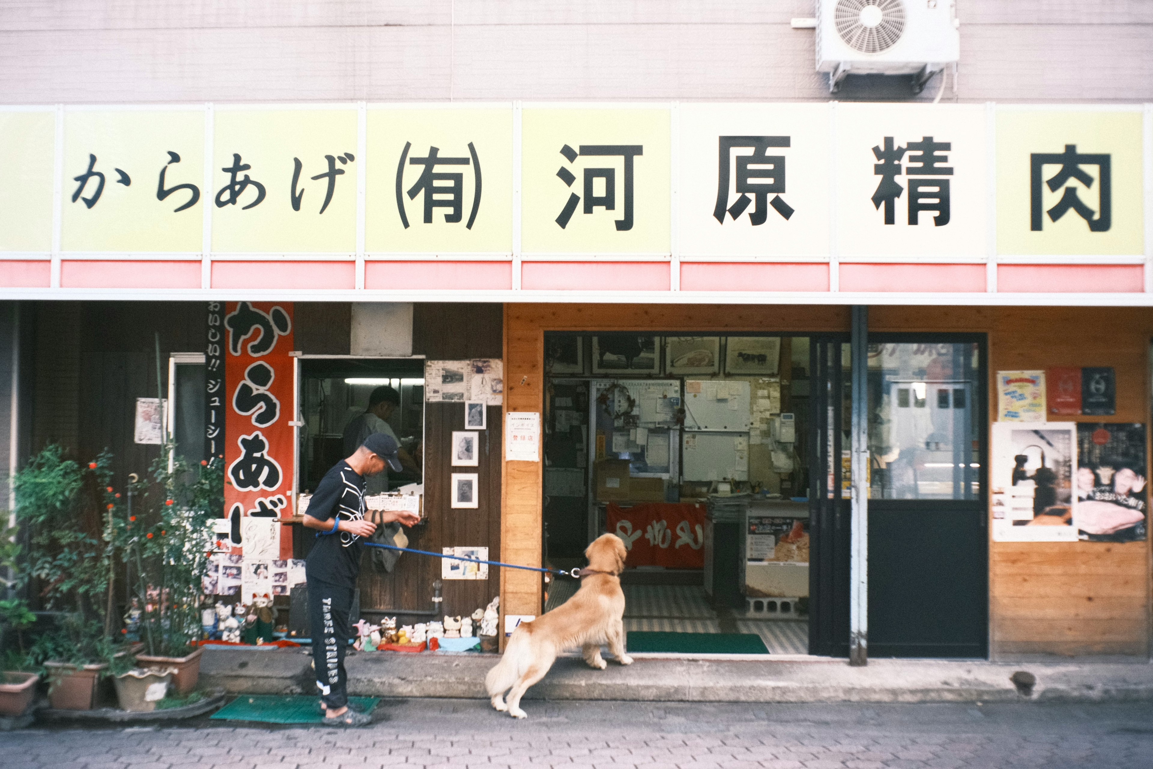 Mann mit Hund vor einer Fleischerei mit einem Schild