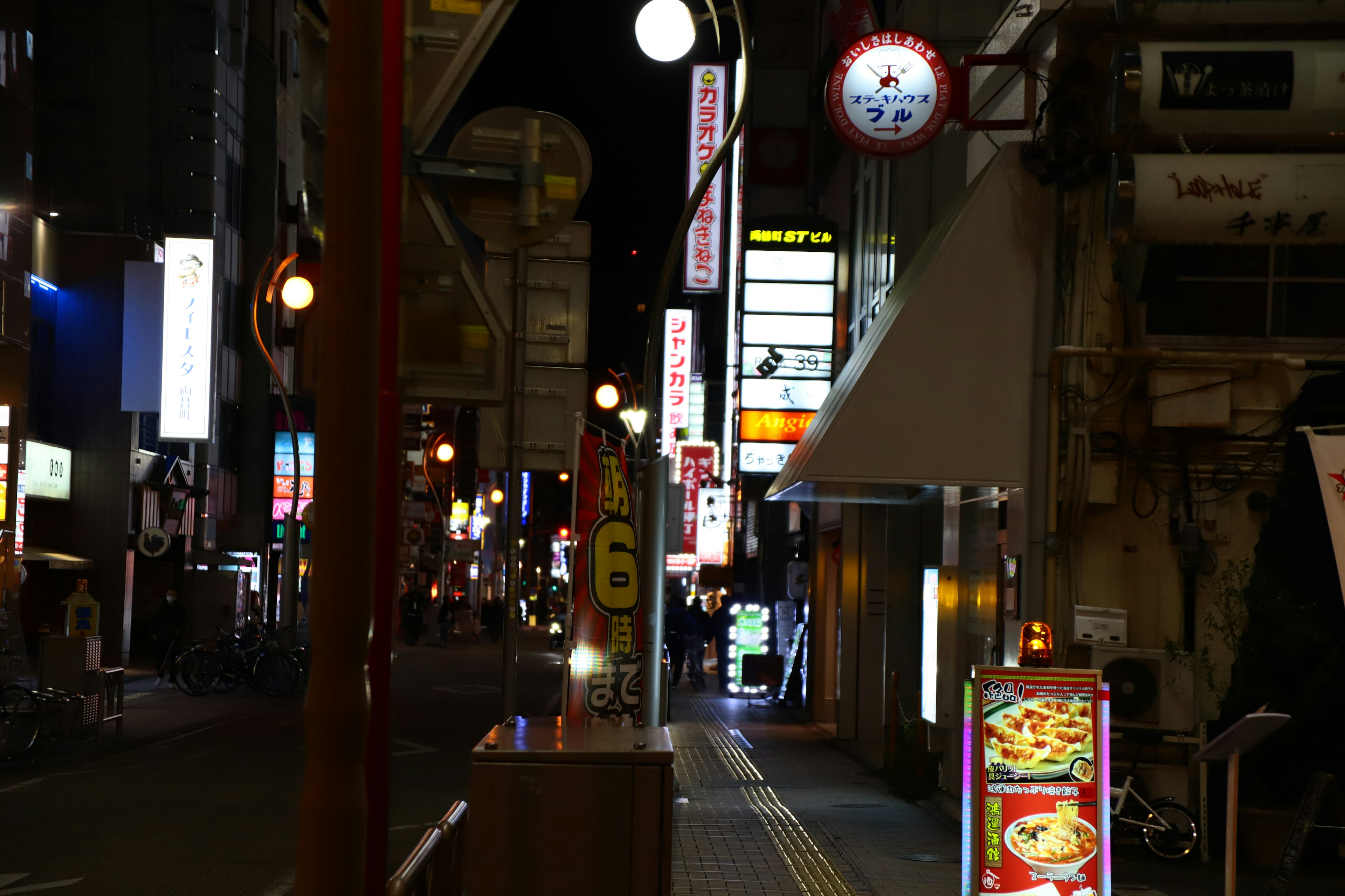 Night street scene with neon signs and storefronts