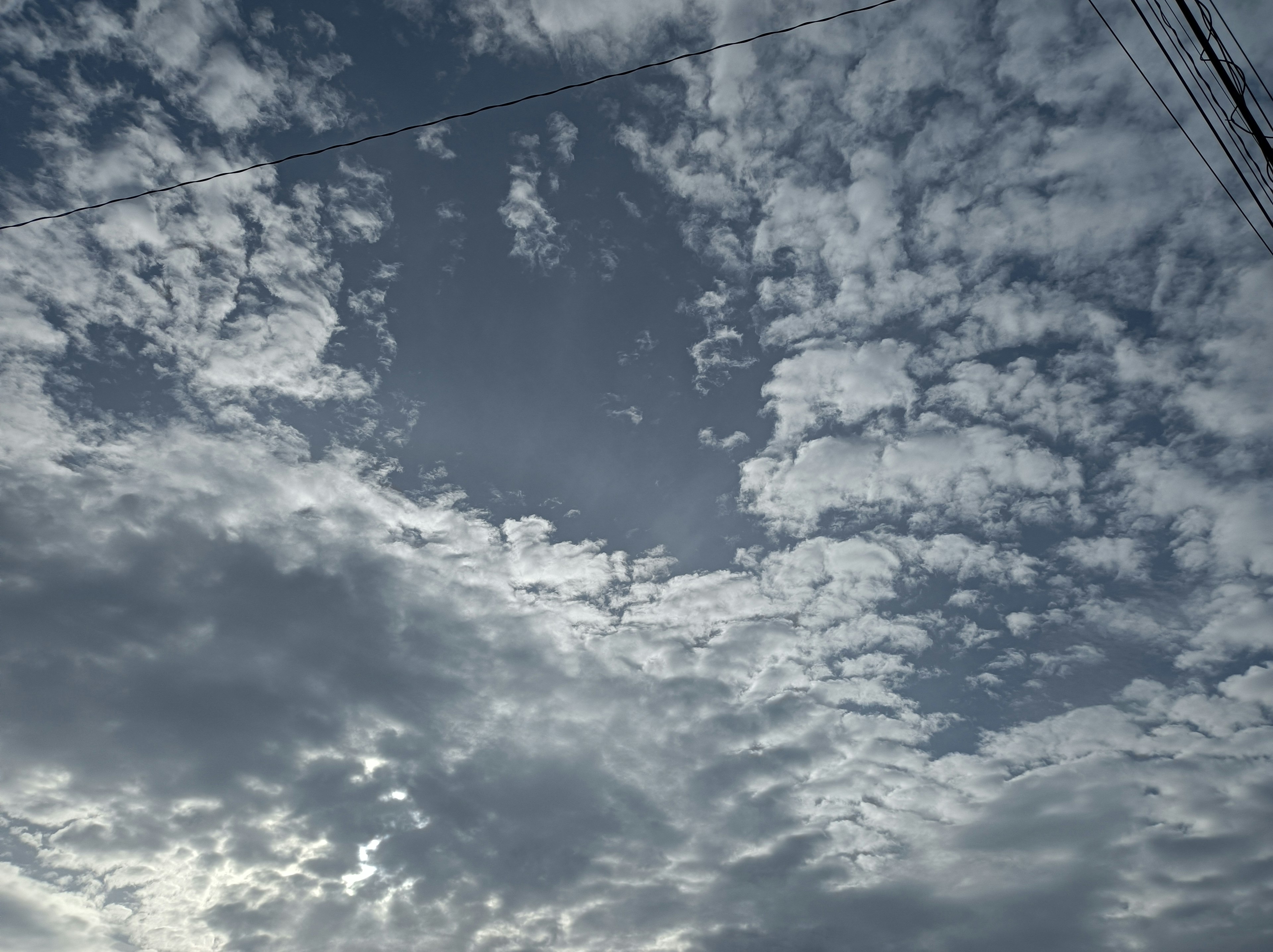 Gray sky with scattered clouds and a small blue hole