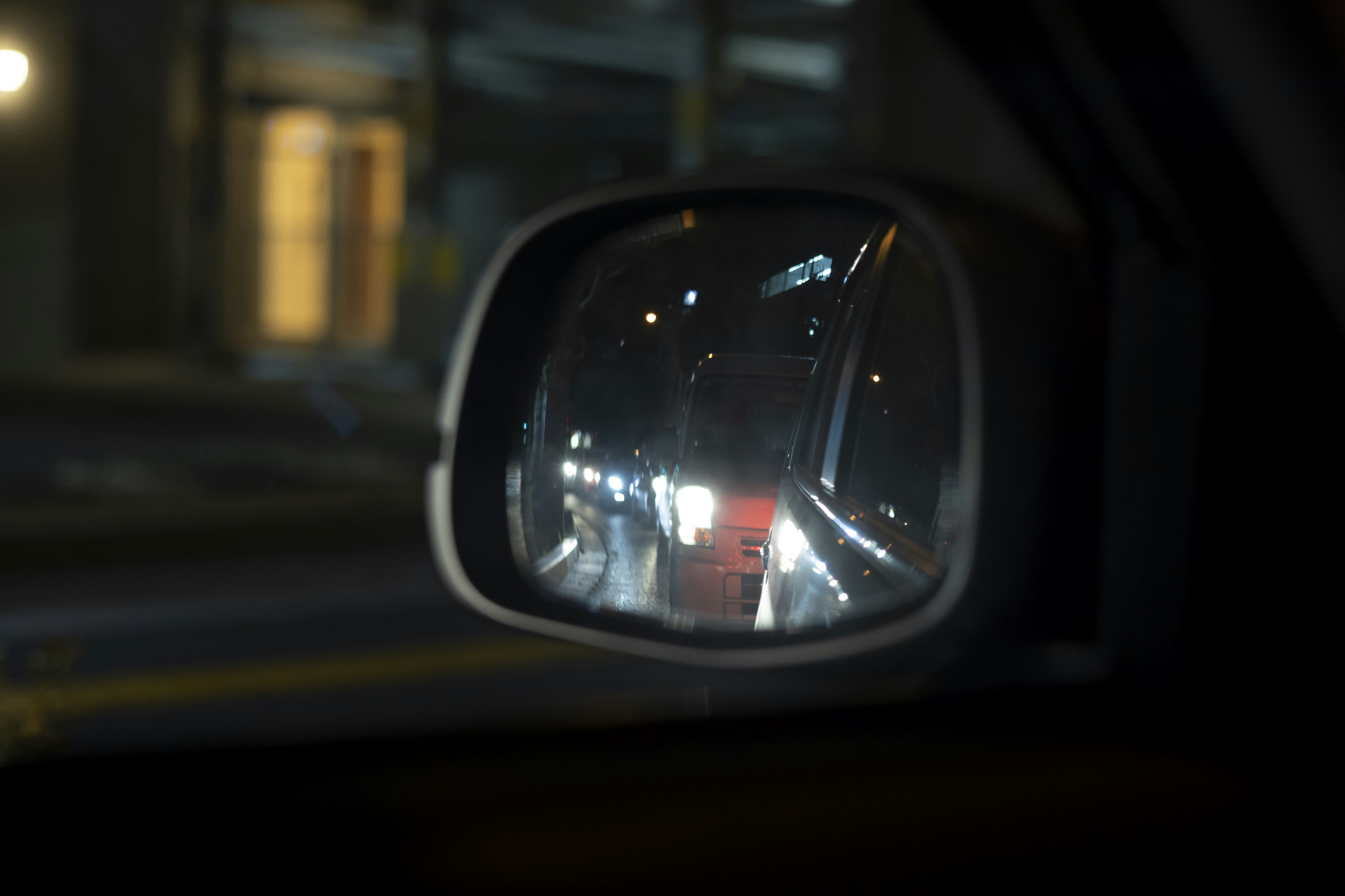 Rear view of car taillights reflected in a side mirror at night