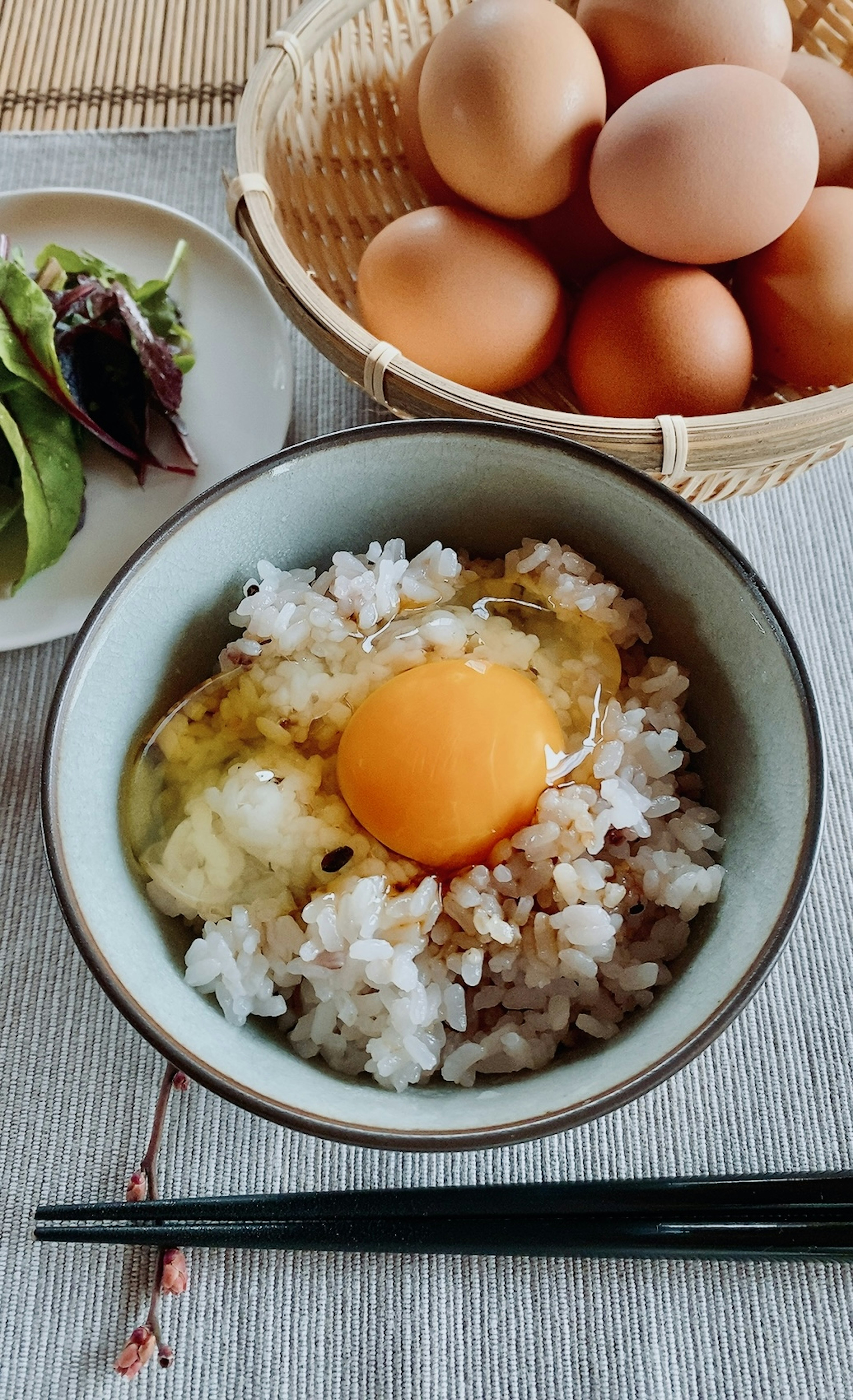 Tazón de arroz cubierto con un huevo crudo y un acompañamiento de verduras frescas