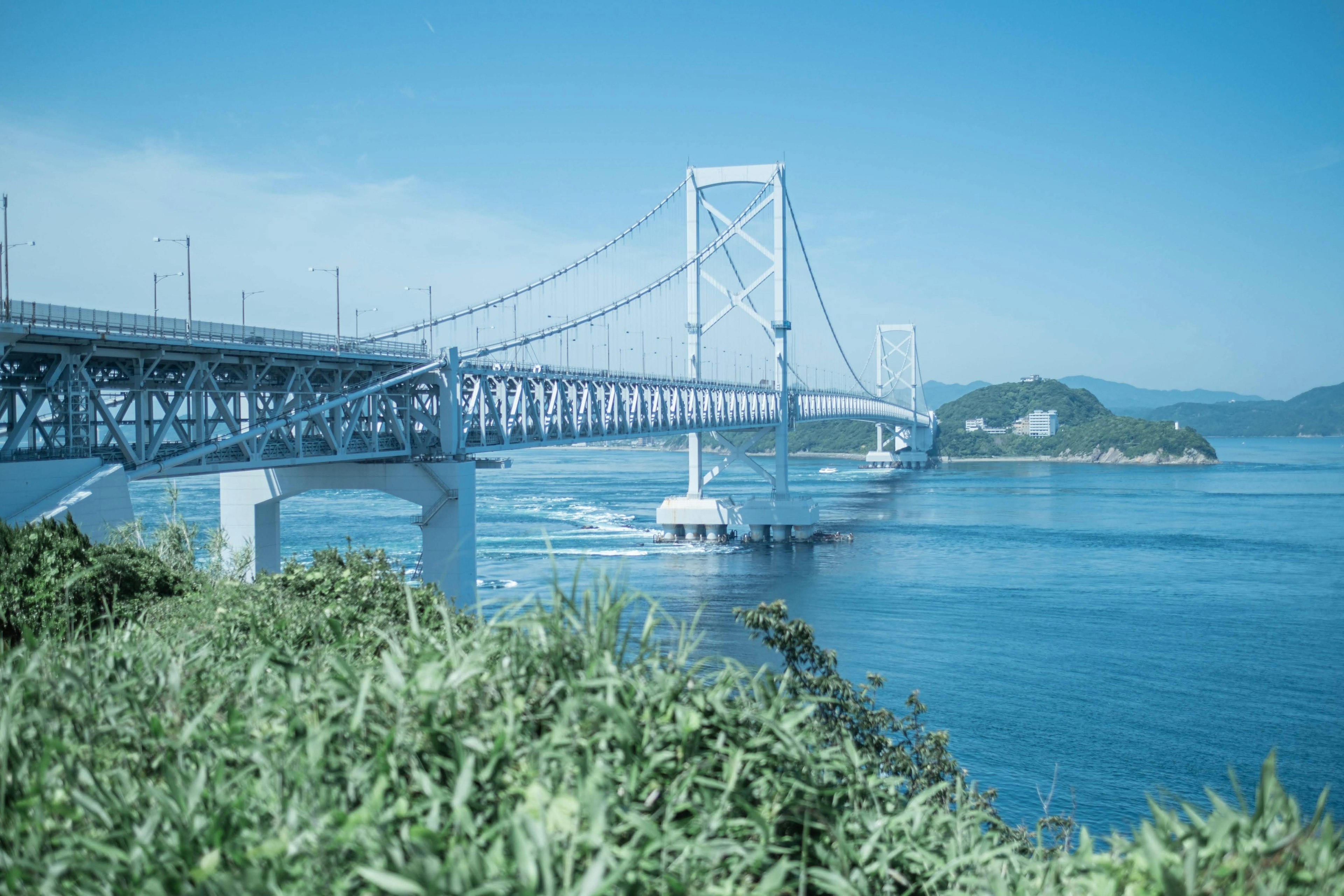 美丽的桥梁横跨蓝色水域，背景有小岛