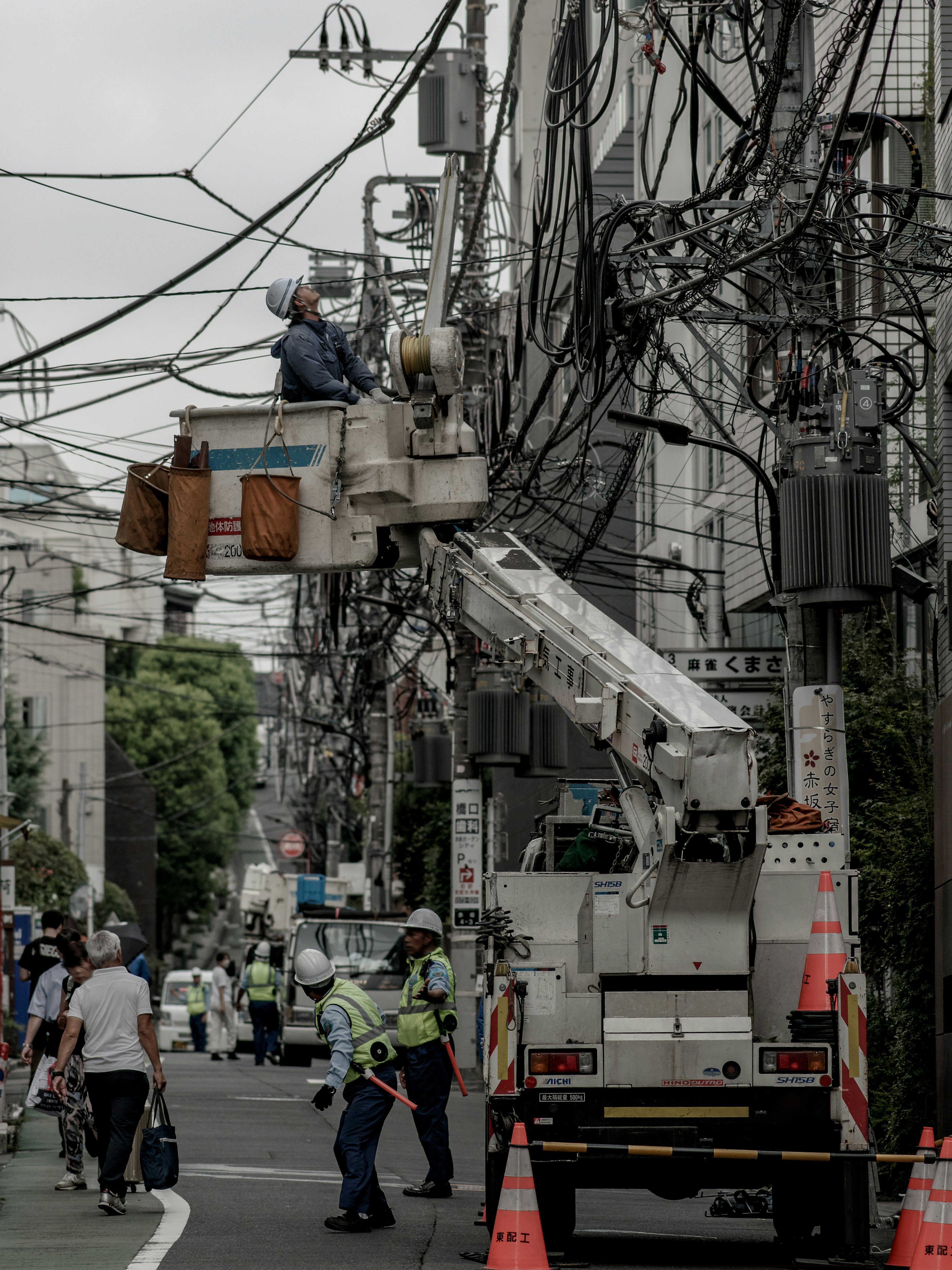 Workers repairing electrical wires in a city setting with a cherry picker