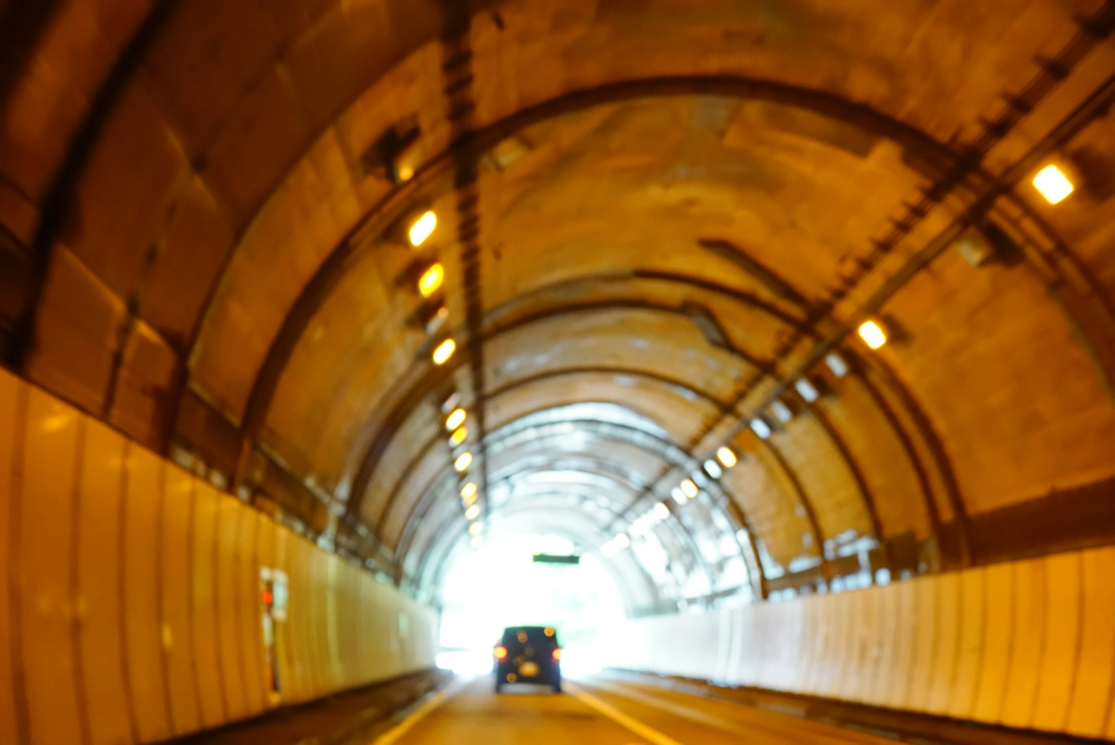 Vue de l'intérieur d'un tunnel avec une voiture s'approchant de la lumière brillante