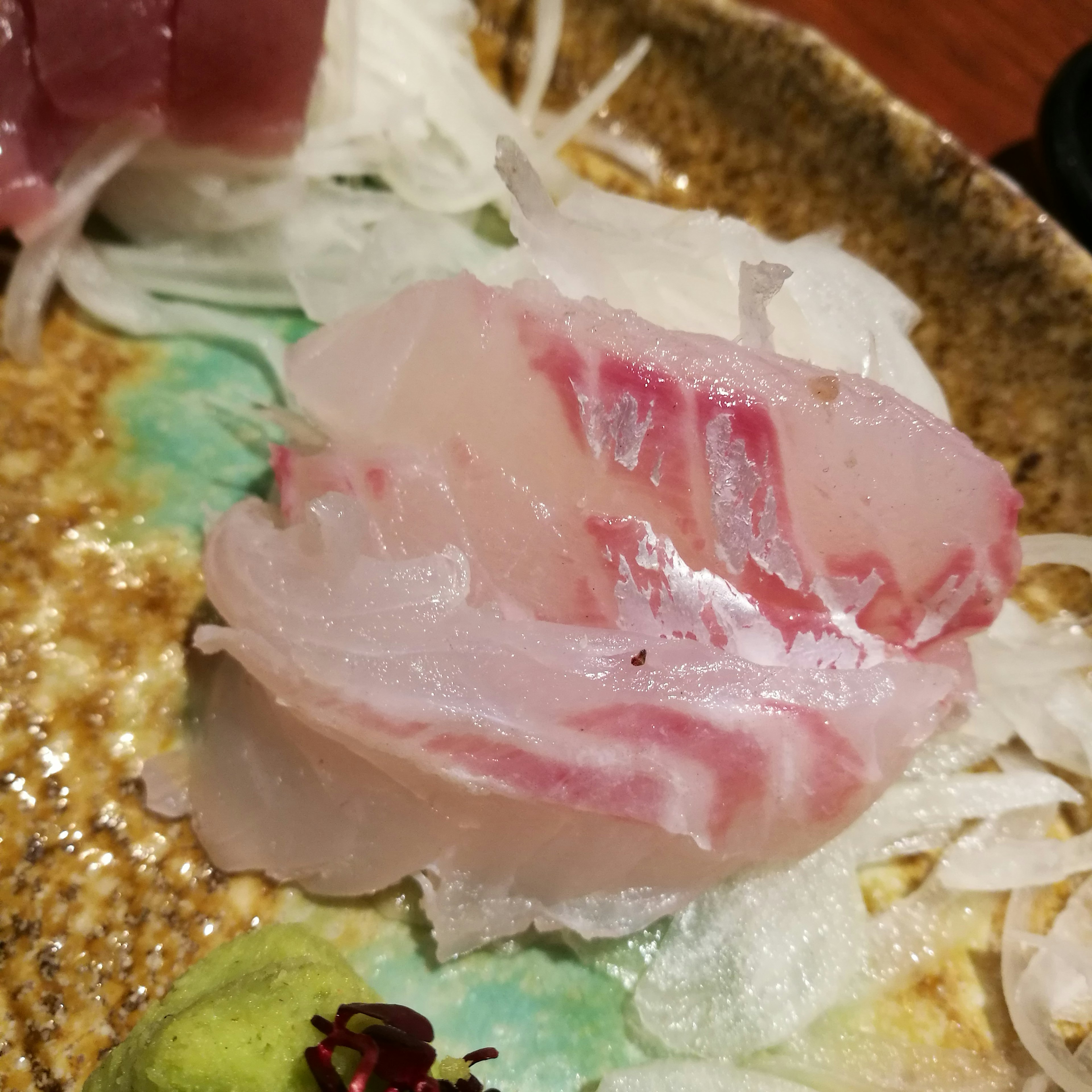 Fresh sashimi slice featuring white fish with red marbling