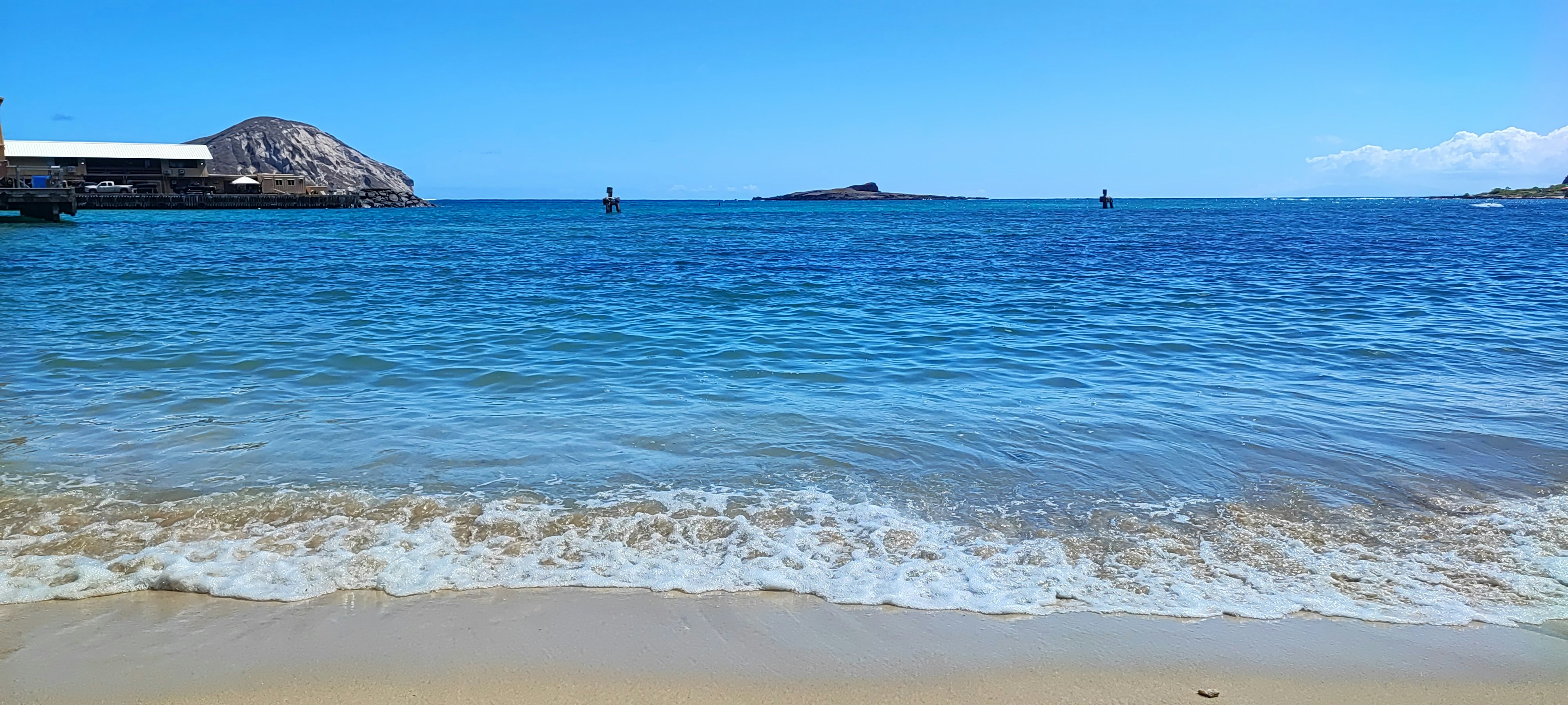 Landschaft mit blauem Ozean und Sandstrand sowie kleinen Booten in der Ferne