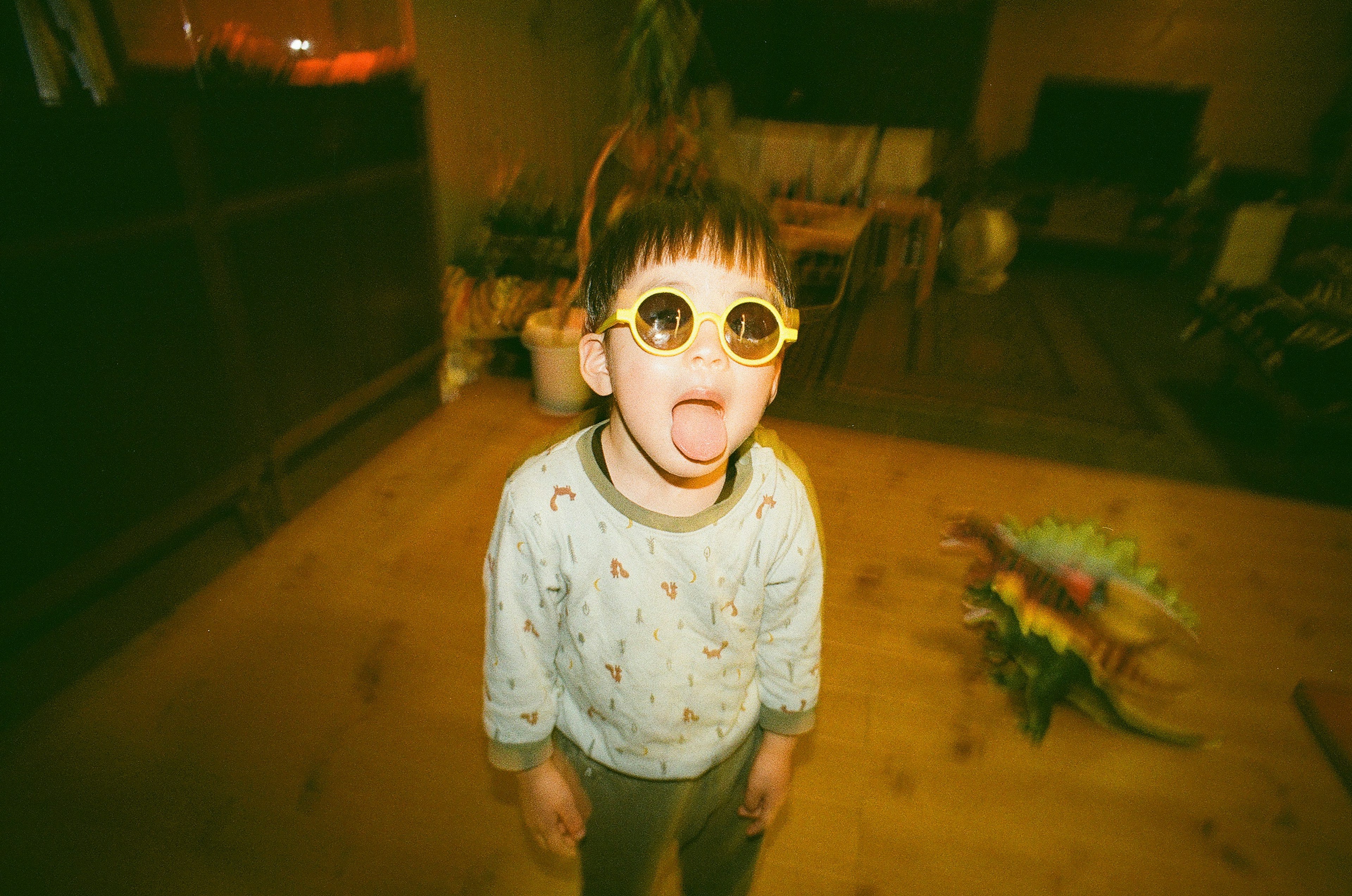 Child wearing sunglasses sticking out tongue in a playful indoor setting