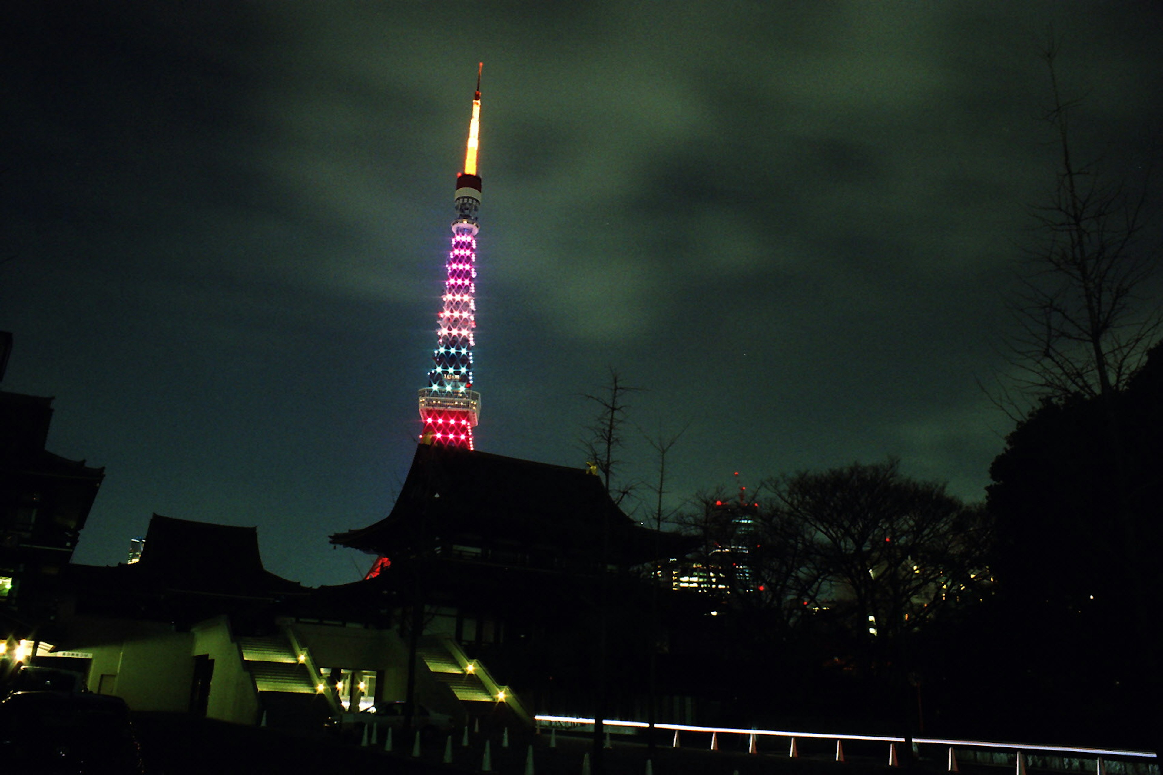 Tokyo Tower nachts beleuchtet mit bunten Lichtern und bewölktem Himmel