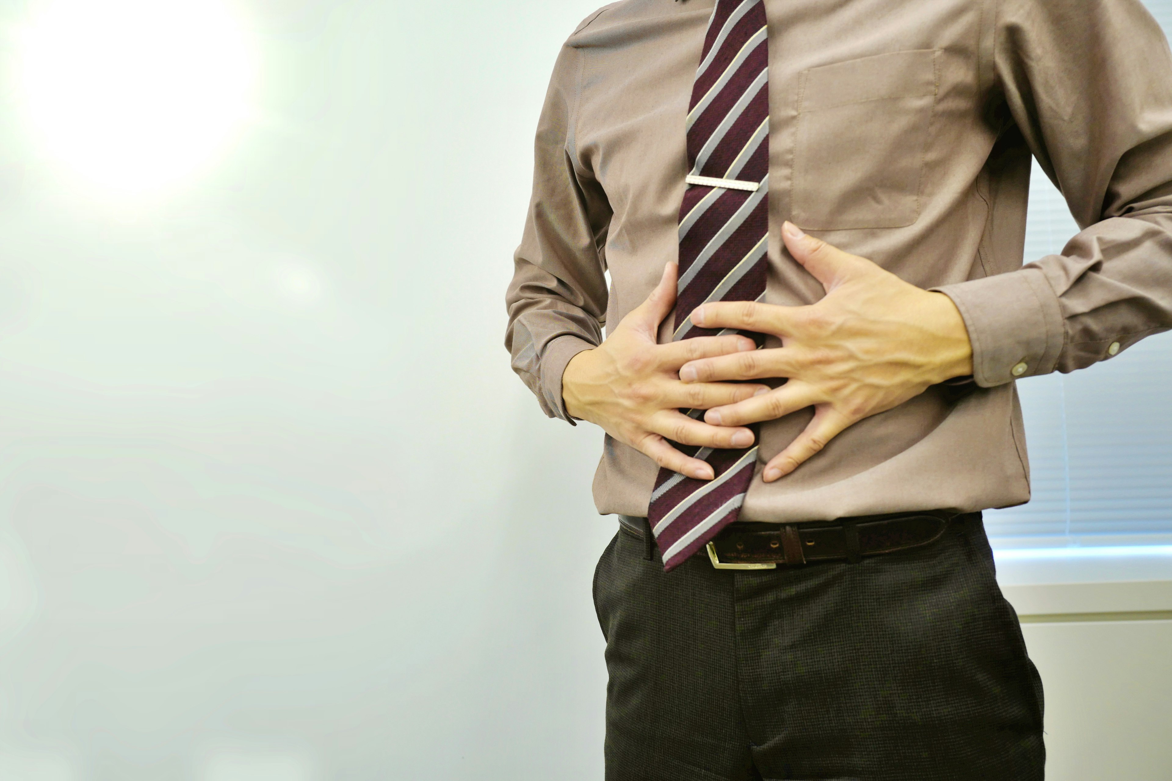 A man in business attire holding his stomach