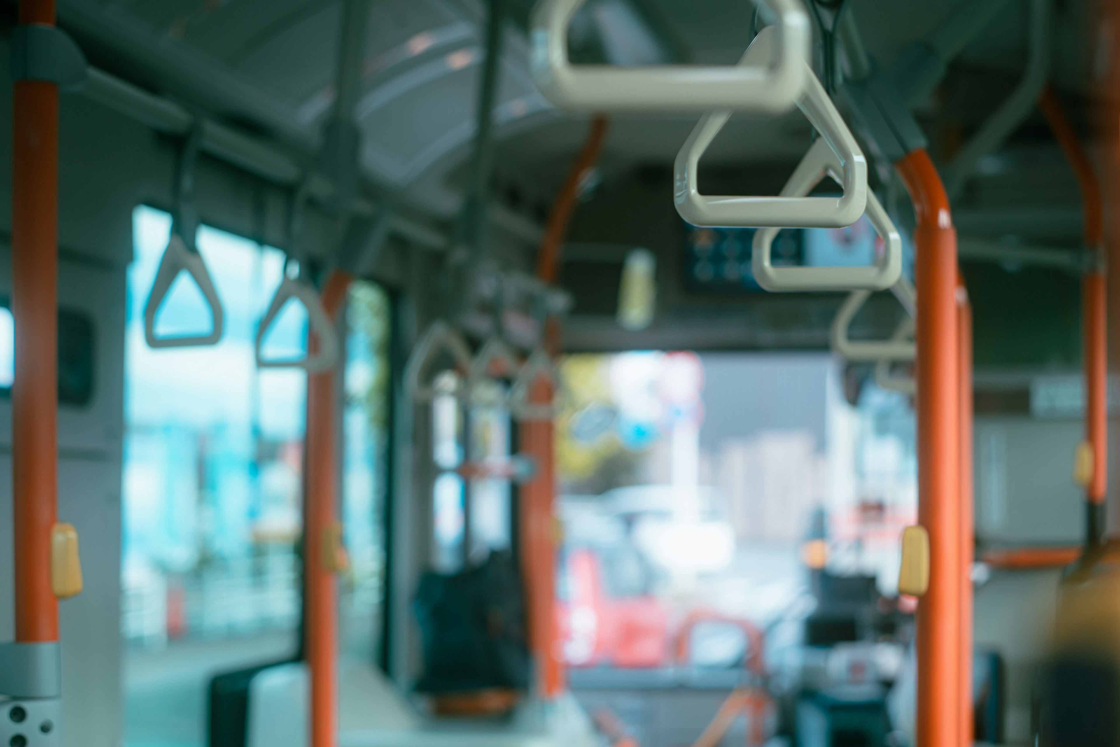 Interior de un autobús mostrando pasamanos y postes naranjas