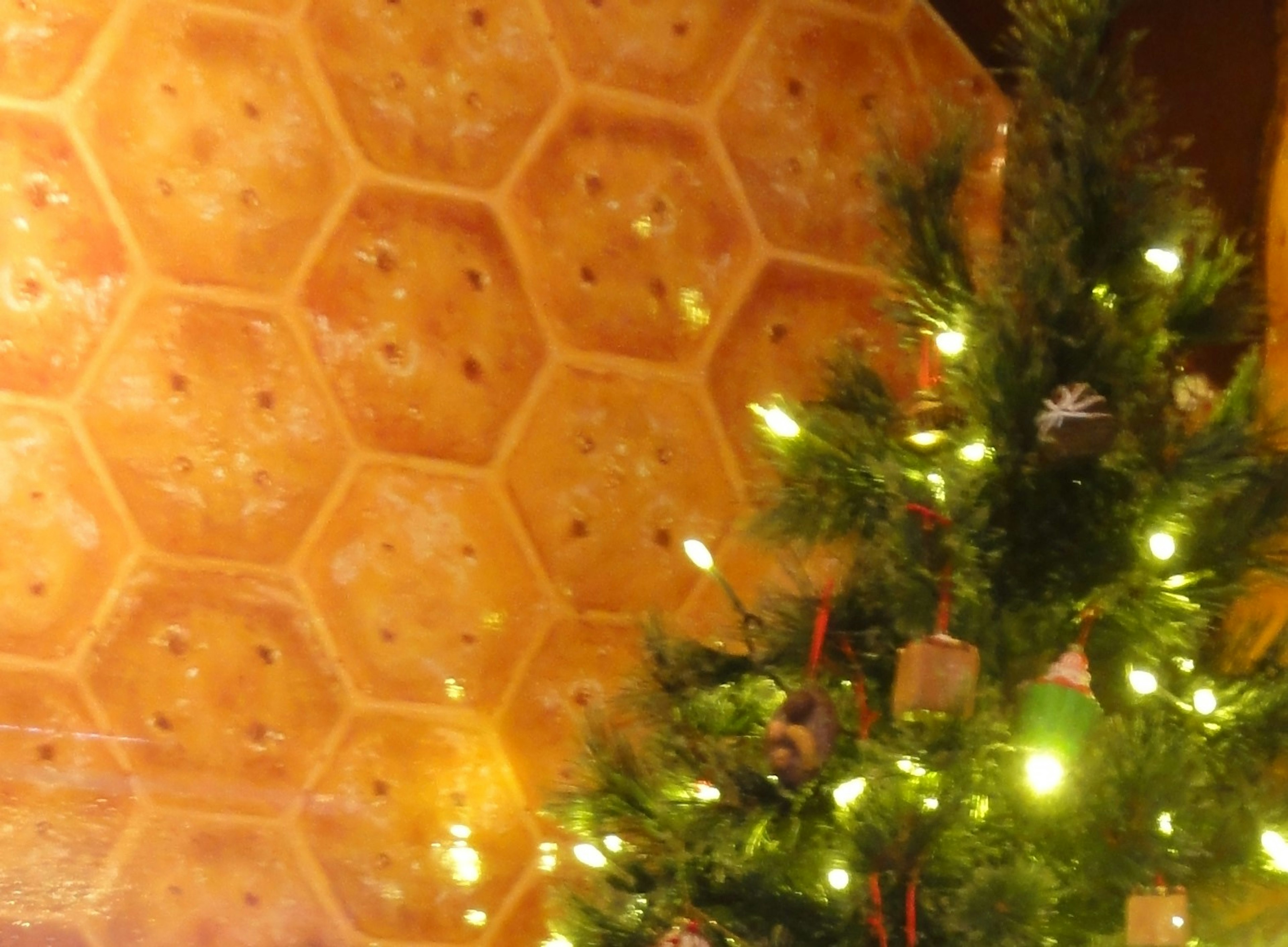 Christmas tree with glowing lights against a honeycomb patterned wall