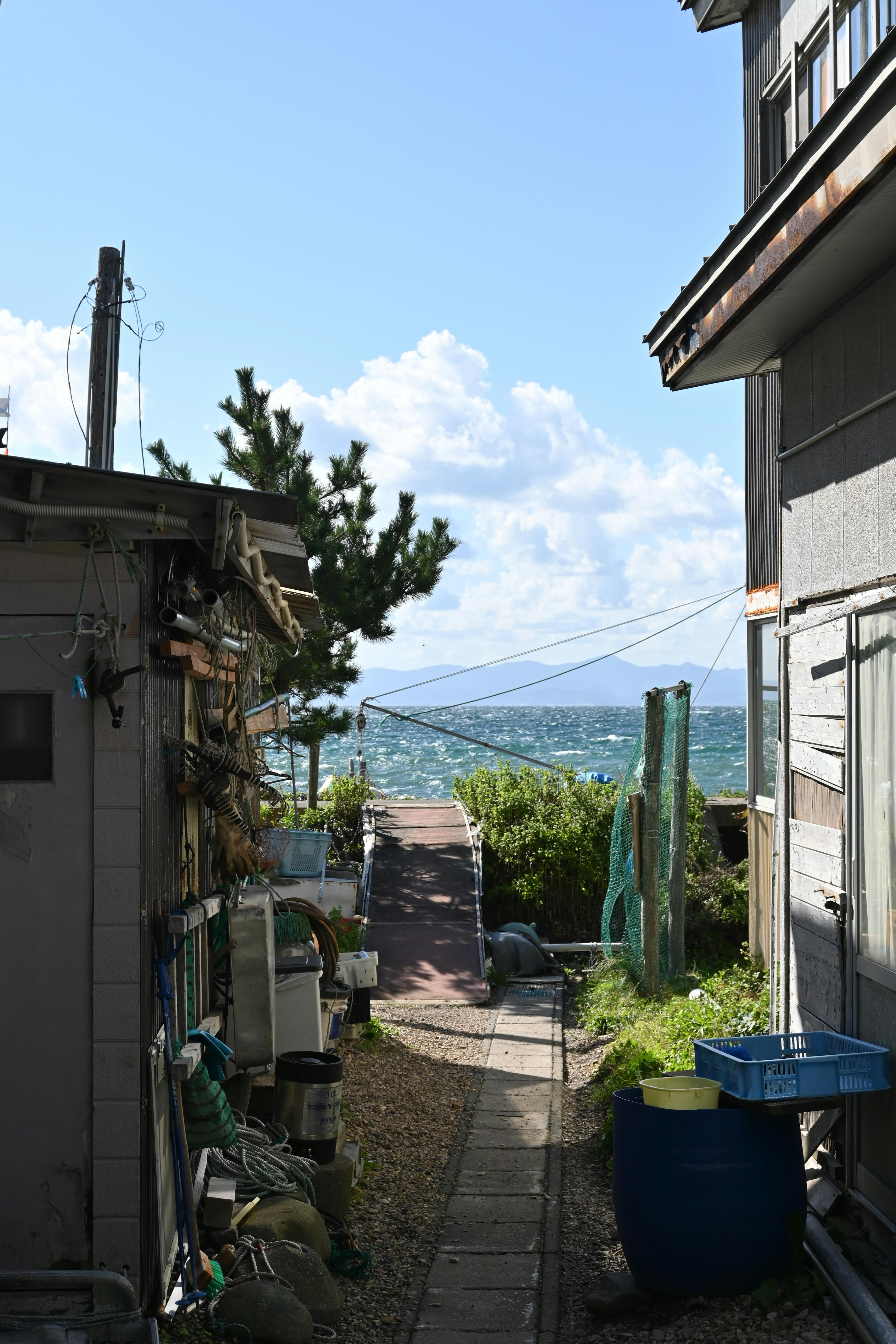 Jalan sempit antara rumah dengan langit biru dan awan