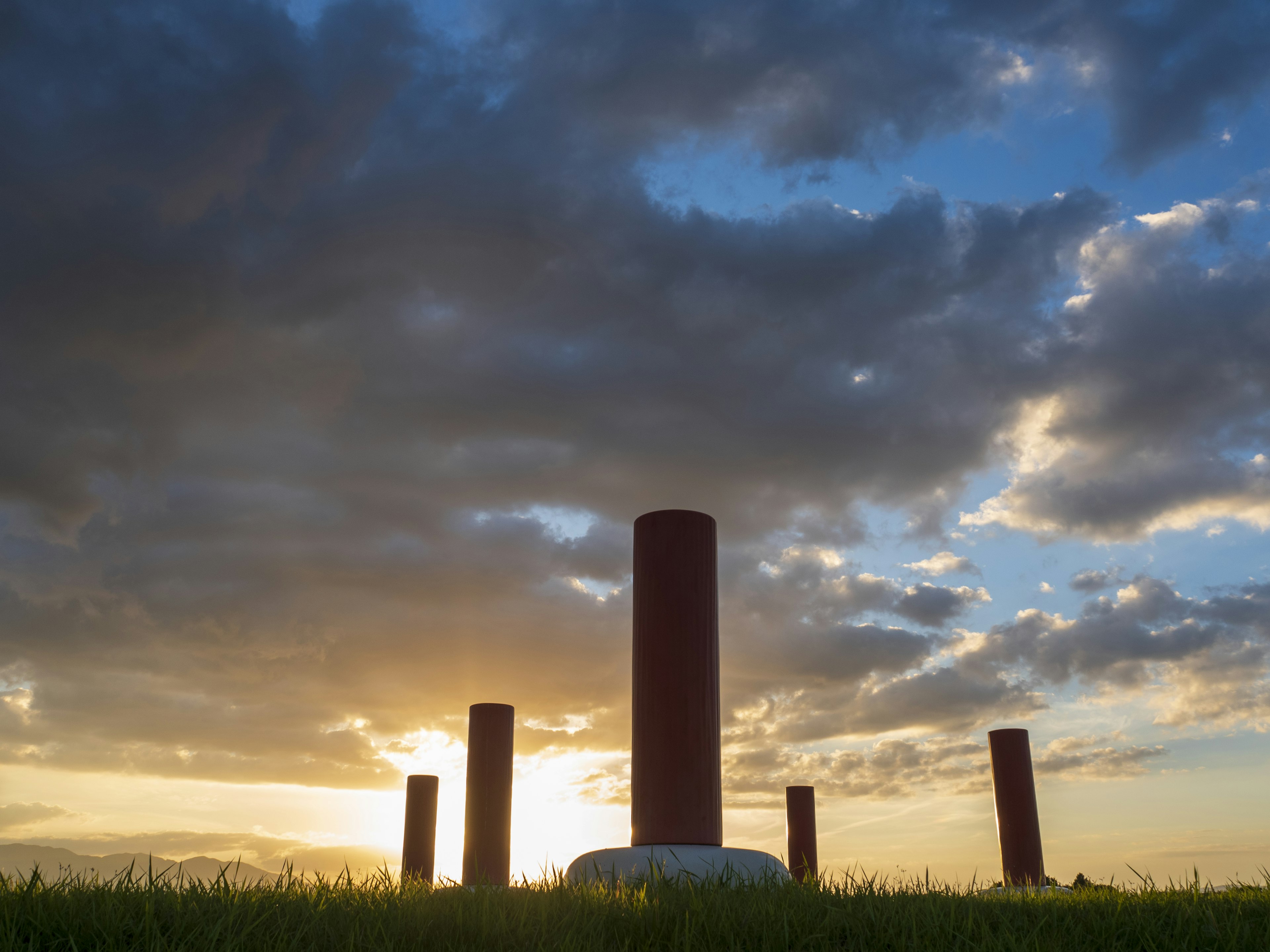 Red pillars silhouetted against a sunset with green grass