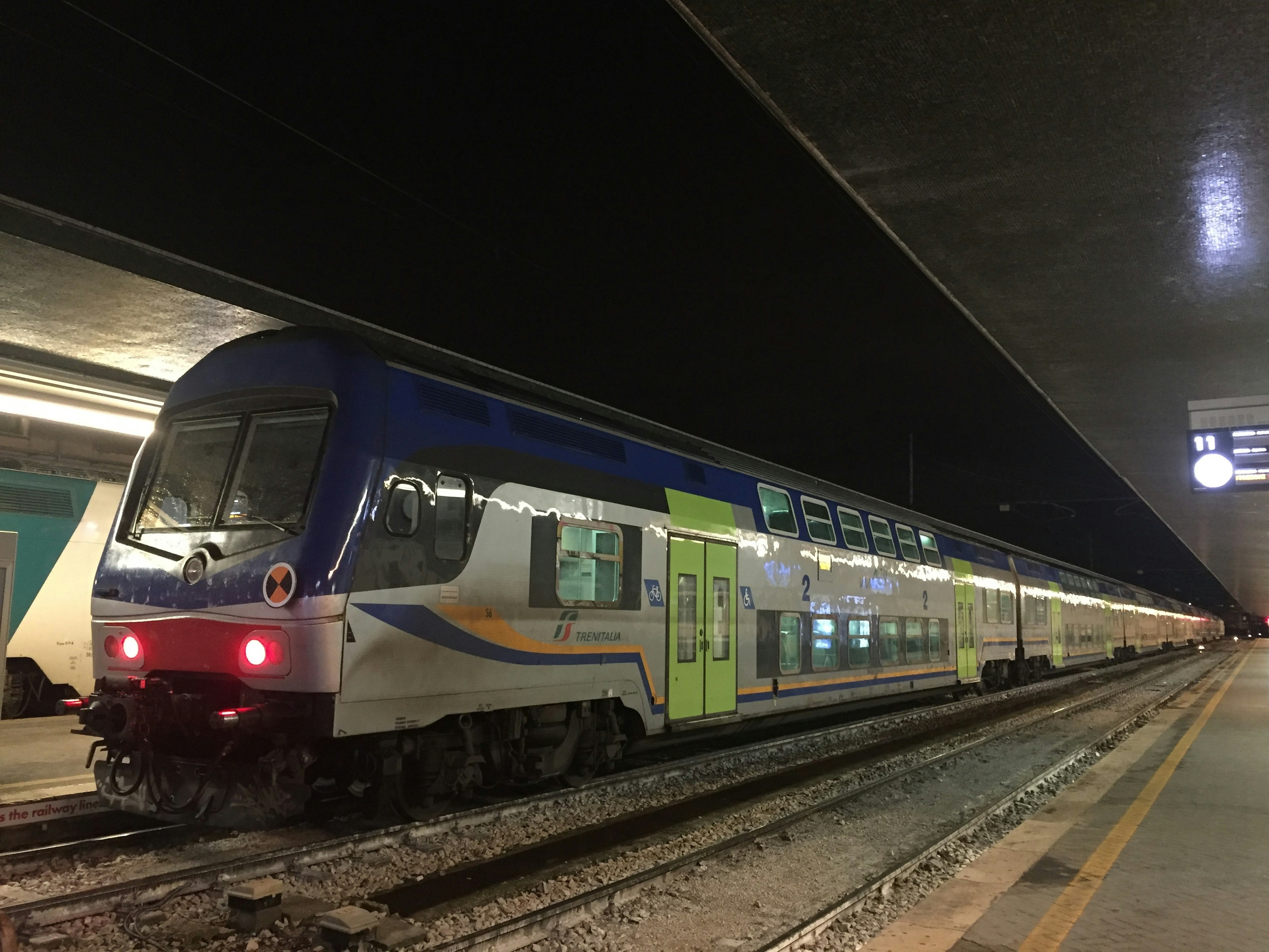 Blue and green train parked at a station night scene