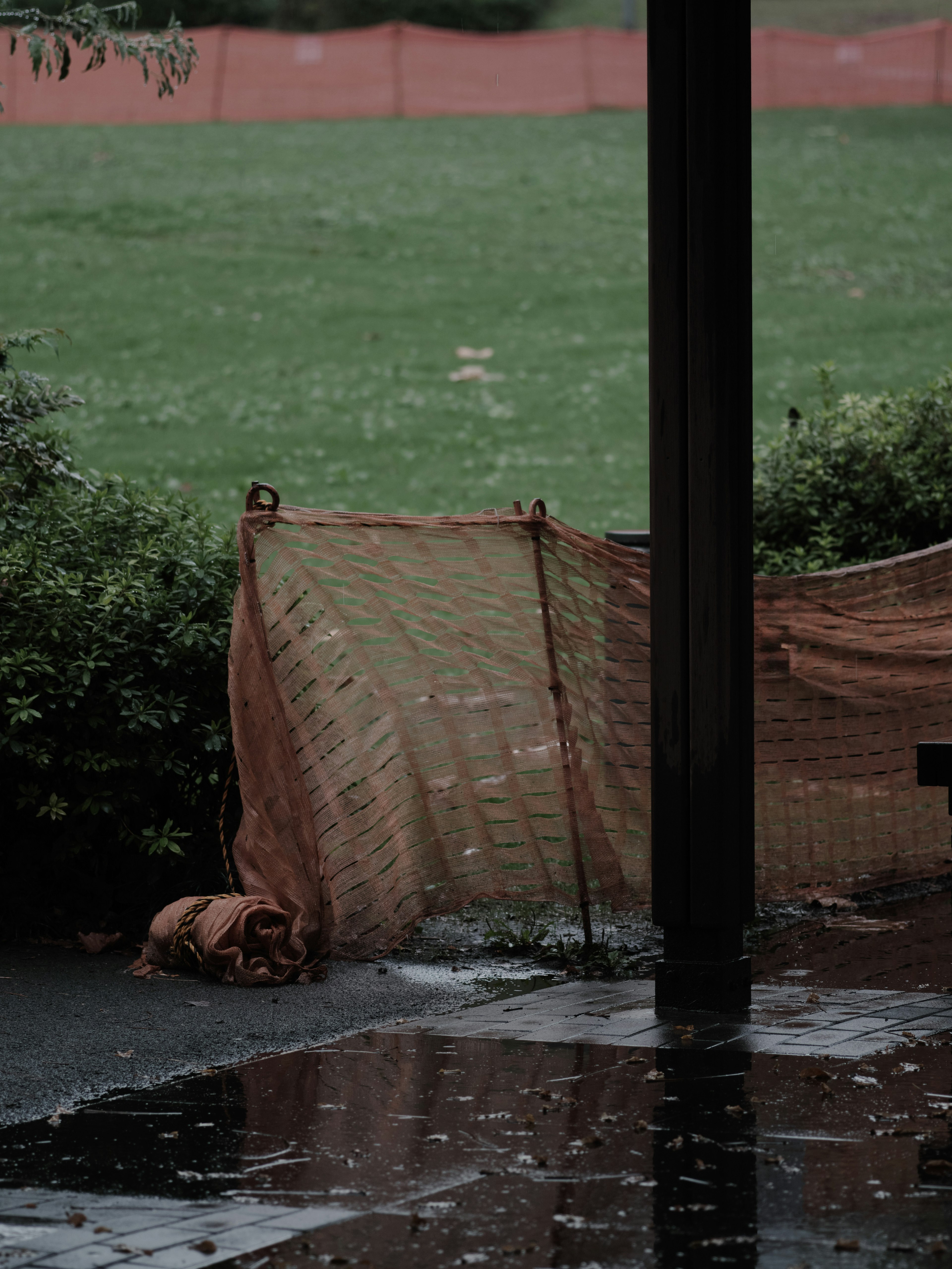 Wet ground with an orange net and a dark post