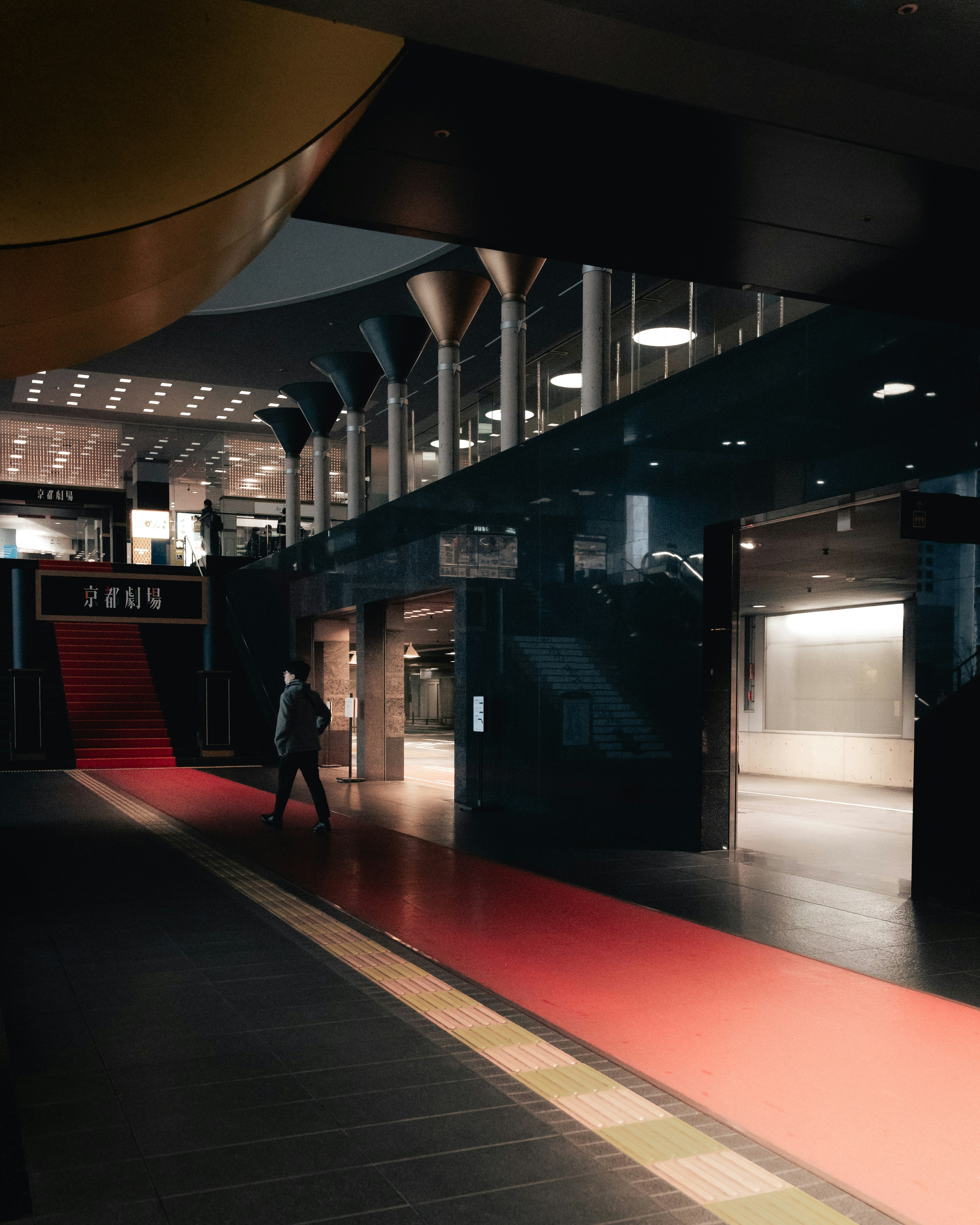 Modern lobby interior with a red carpet bright lighting and a person walking