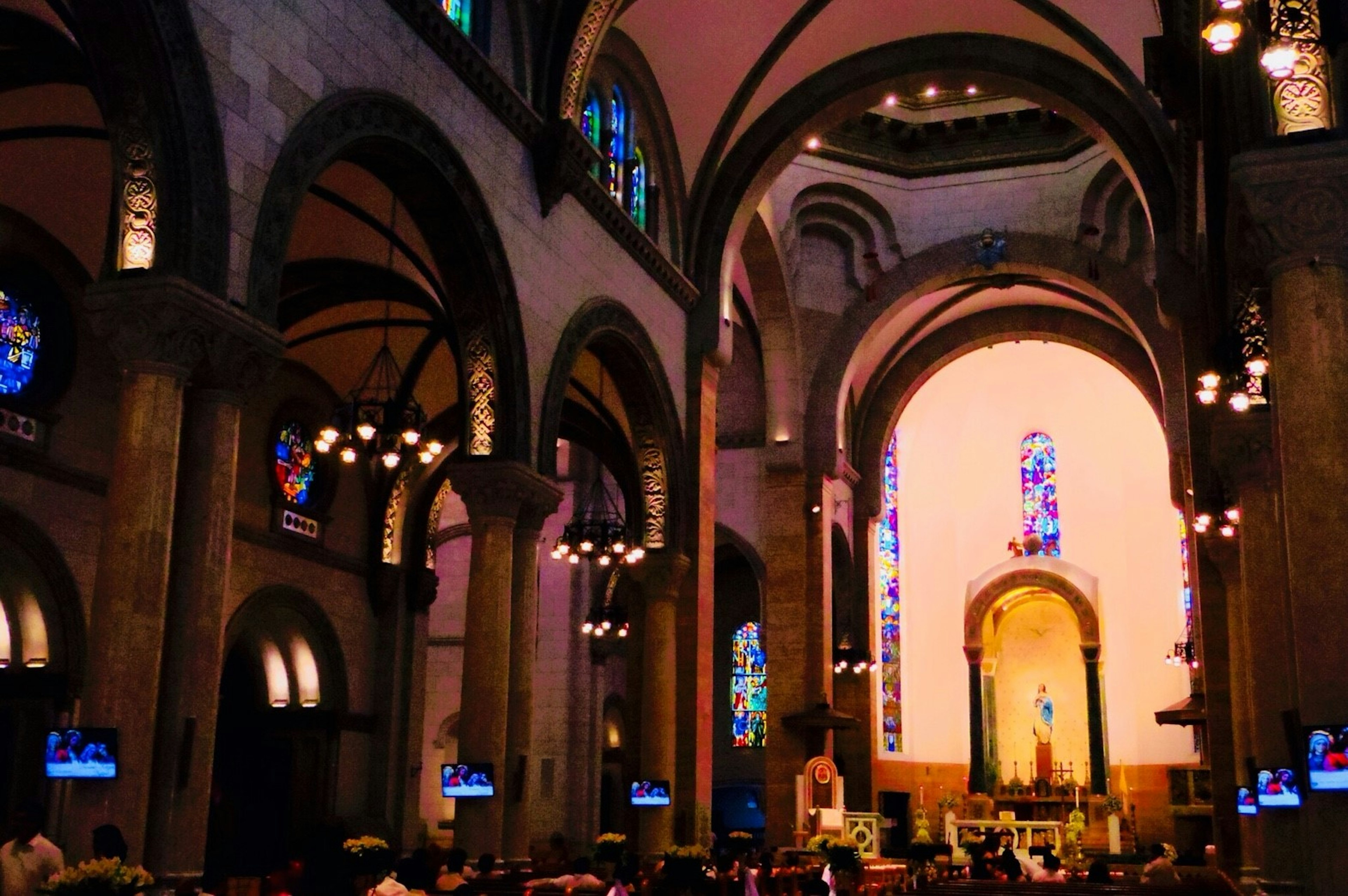 Interior de una hermosa iglesia con techos en arco vitrales coloridos y luz que entra detrás del altar