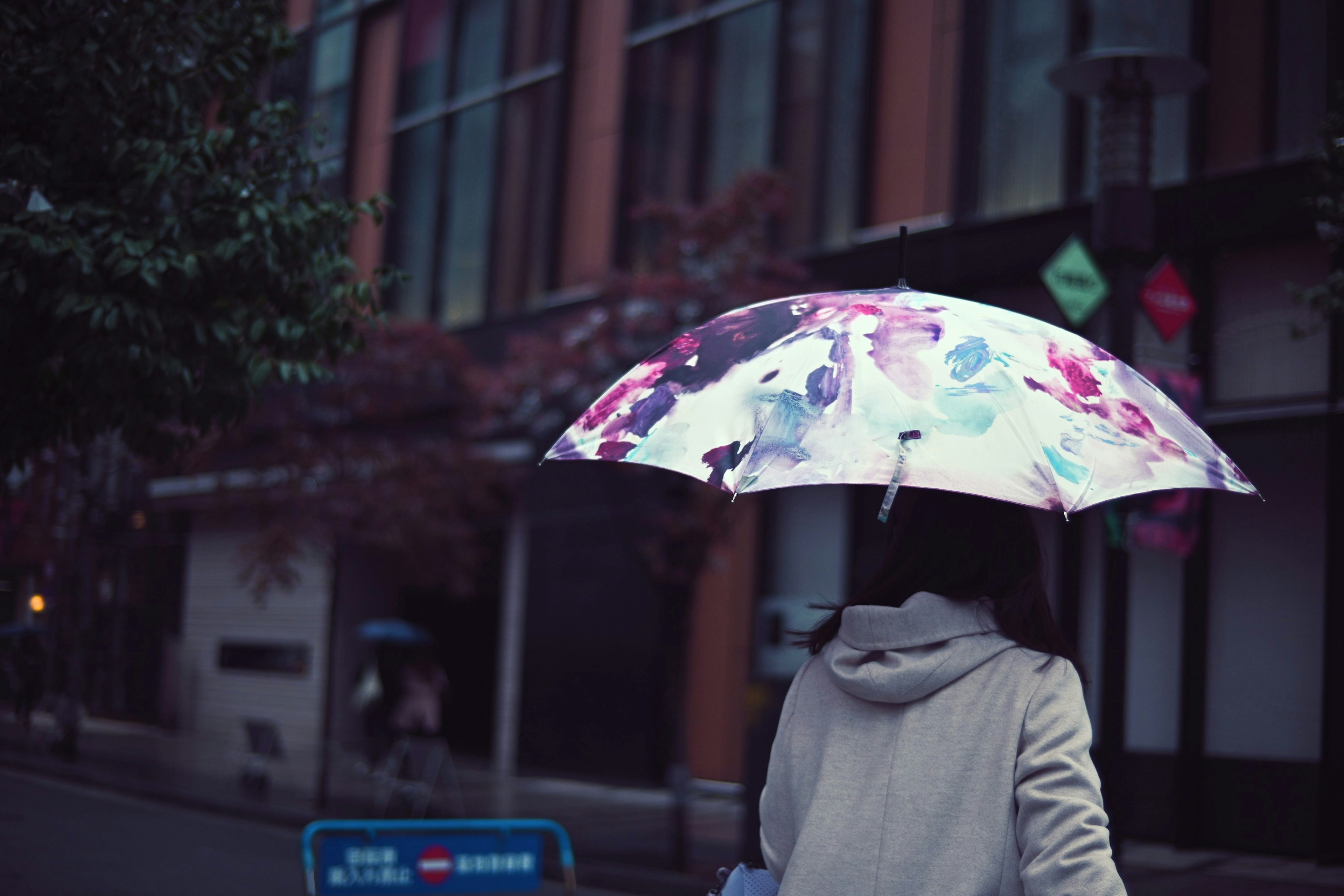 傘を持って歩く女性の後ろ姿とカラフルな花柄の傘