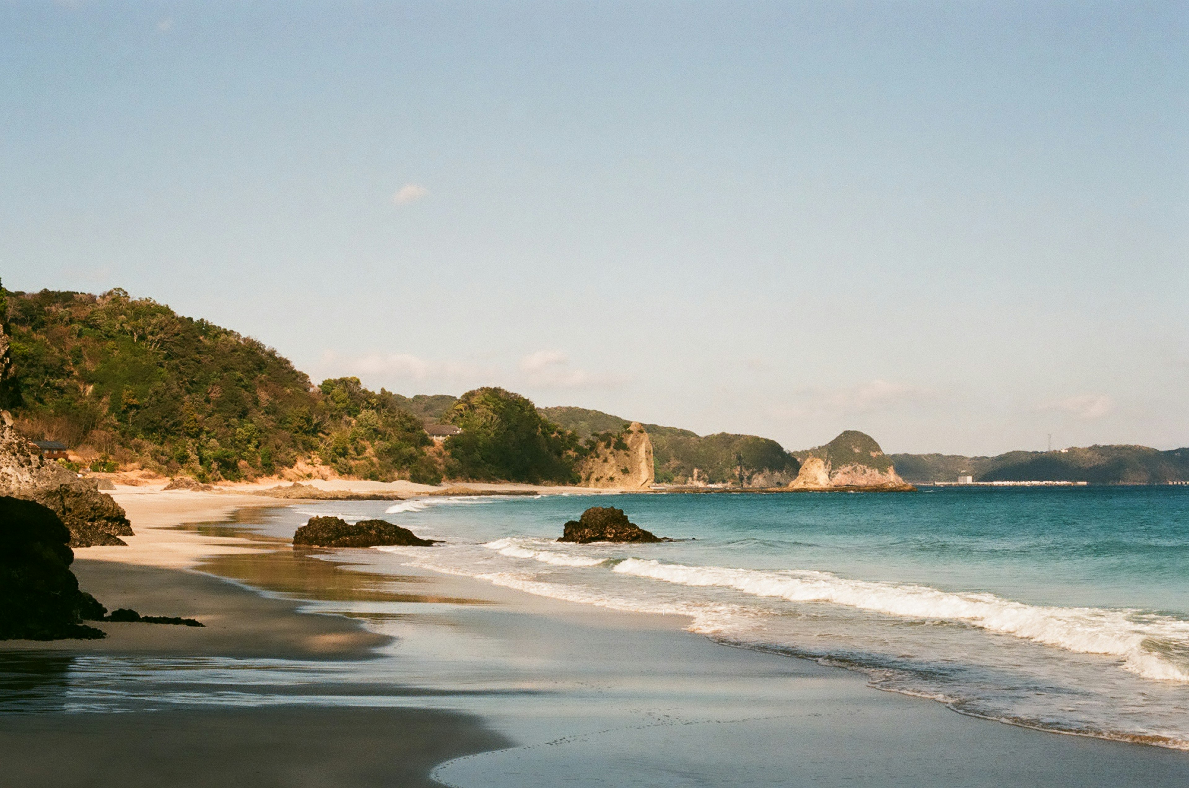 ทิวทัศน์ชายหาดที่สวยงามพร้อมชายฝั่งที่เรียบและมหาสมุทรสีน้ำเงิน