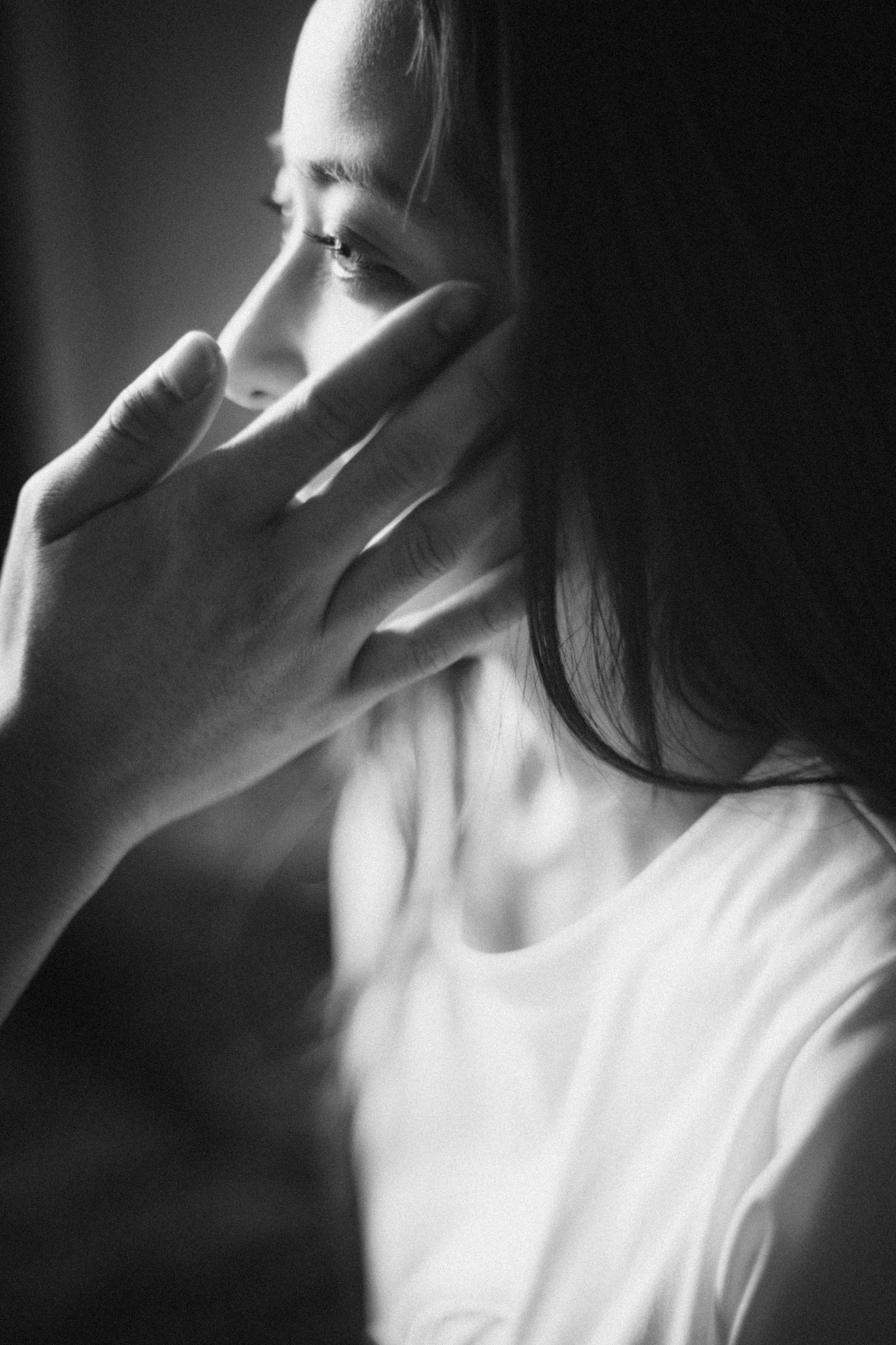 Black and white image of a woman's profile with a hand touching her face