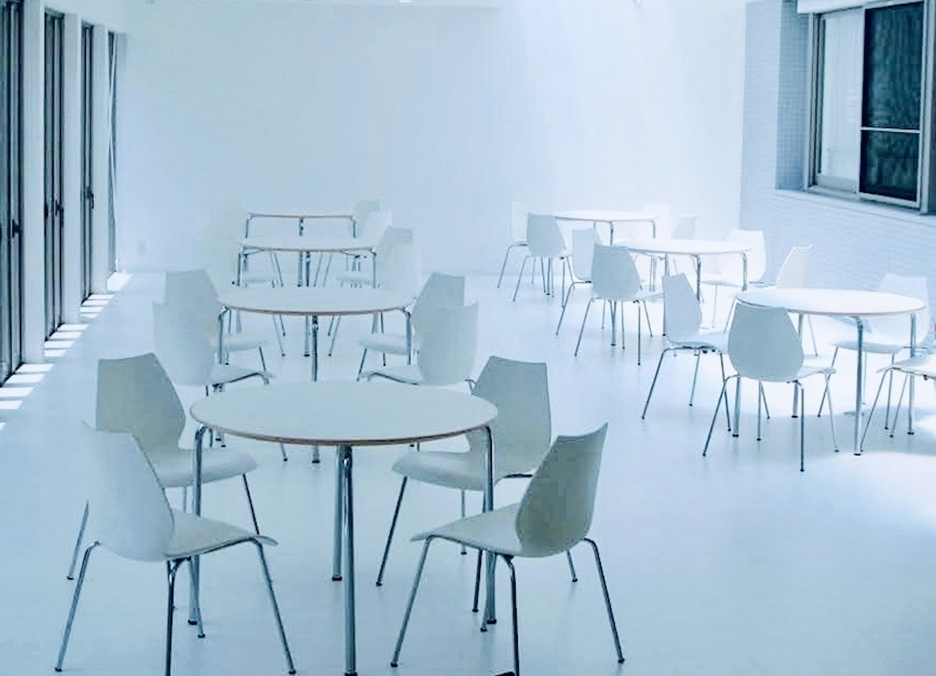 Minimalist interior with white walls and tables arranged