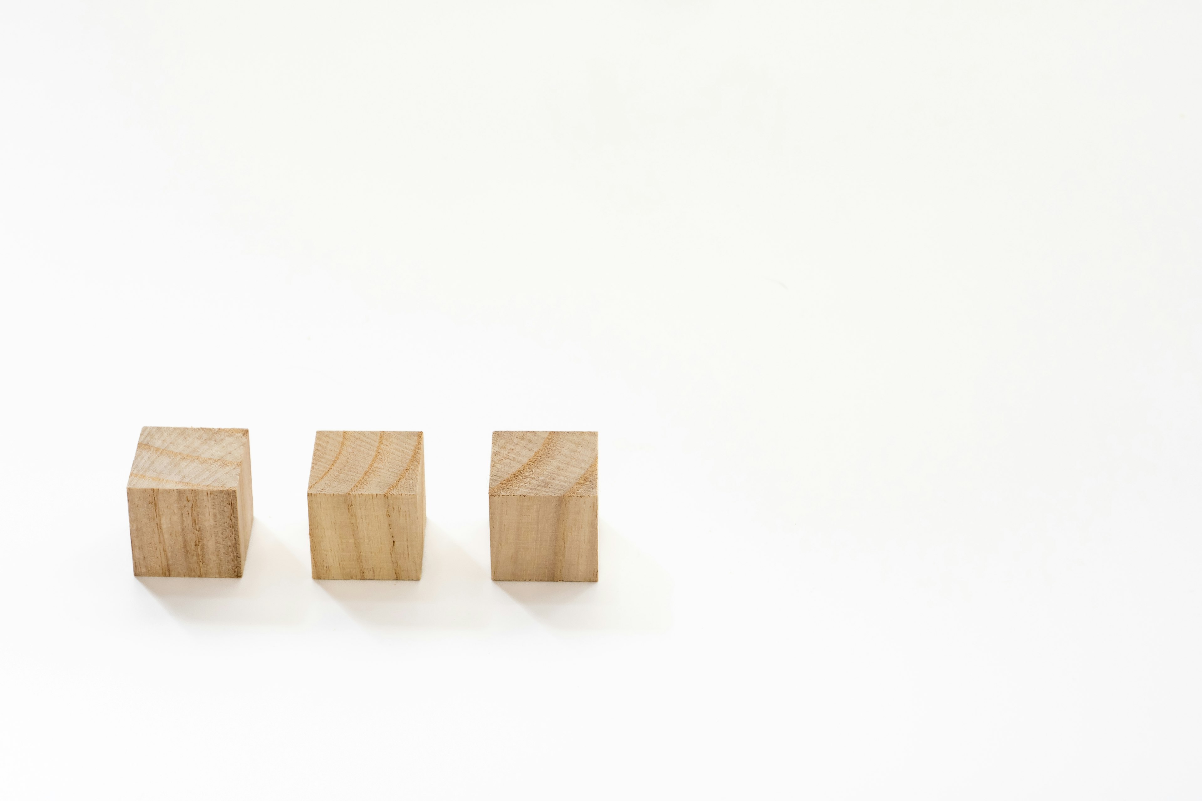 Trois cubes en bois disposés sur un fond blanc