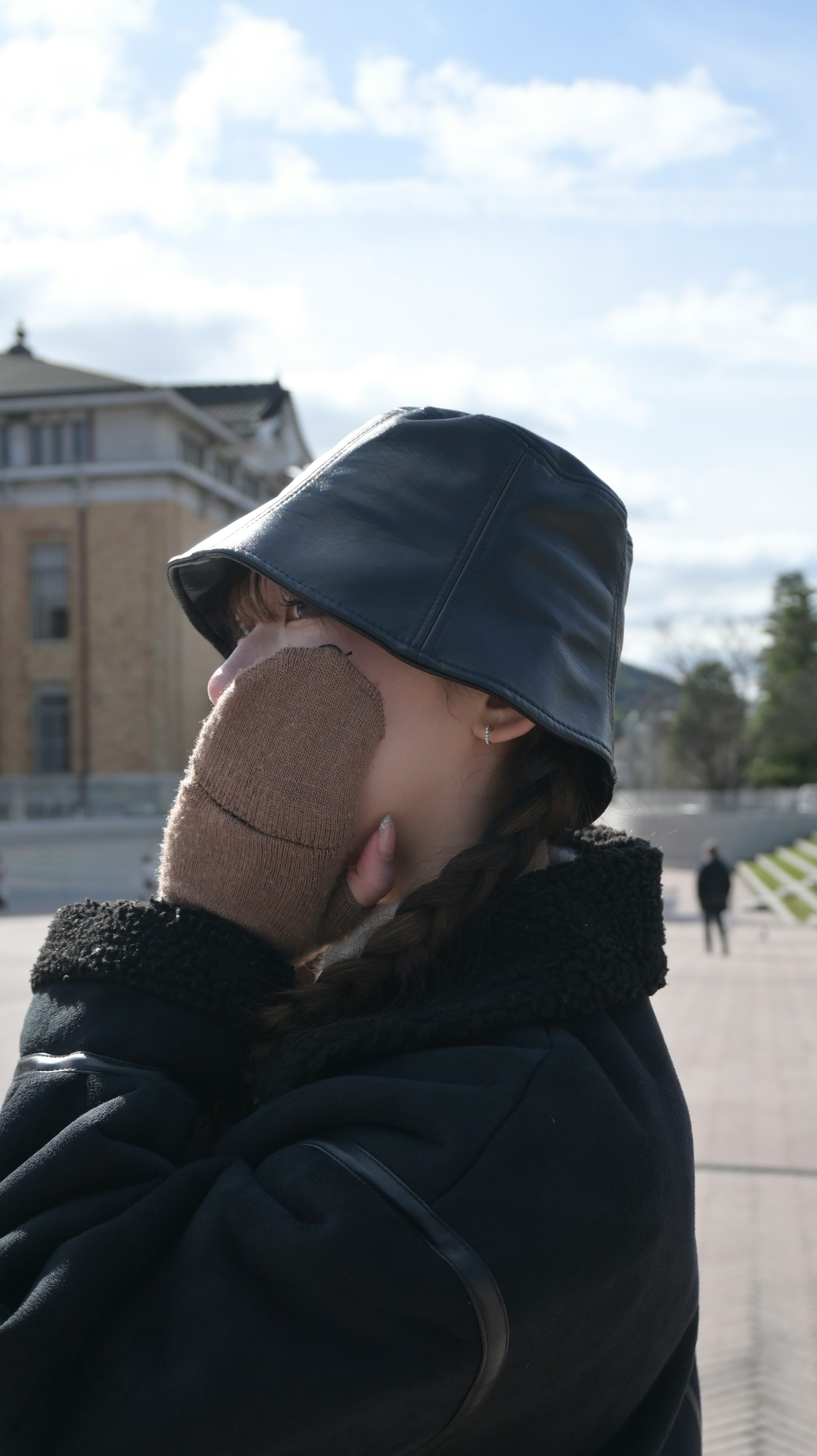 Woman wearing a bucket hat covering her face with her hand