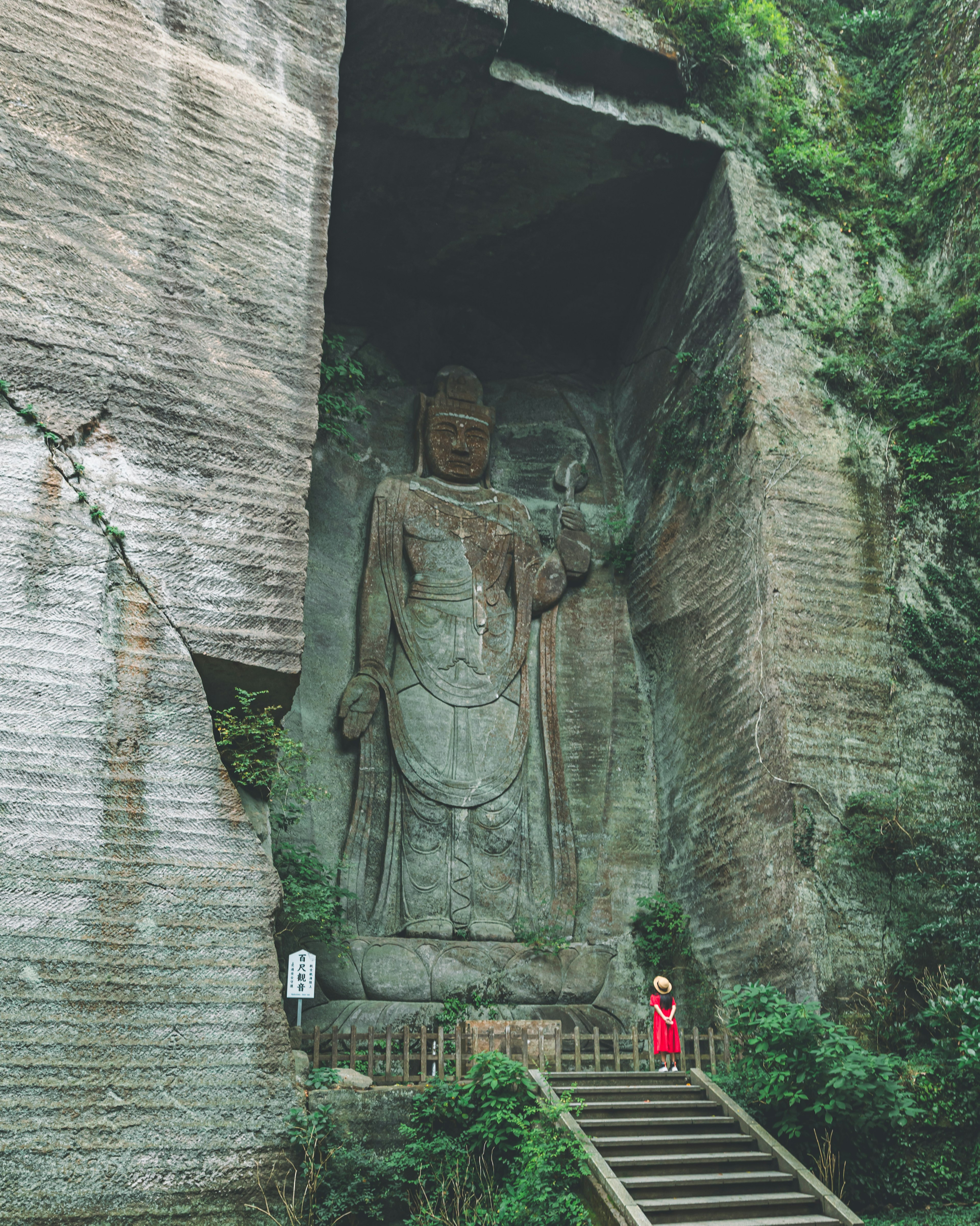 大きな彫刻の仏像と階段を登る人