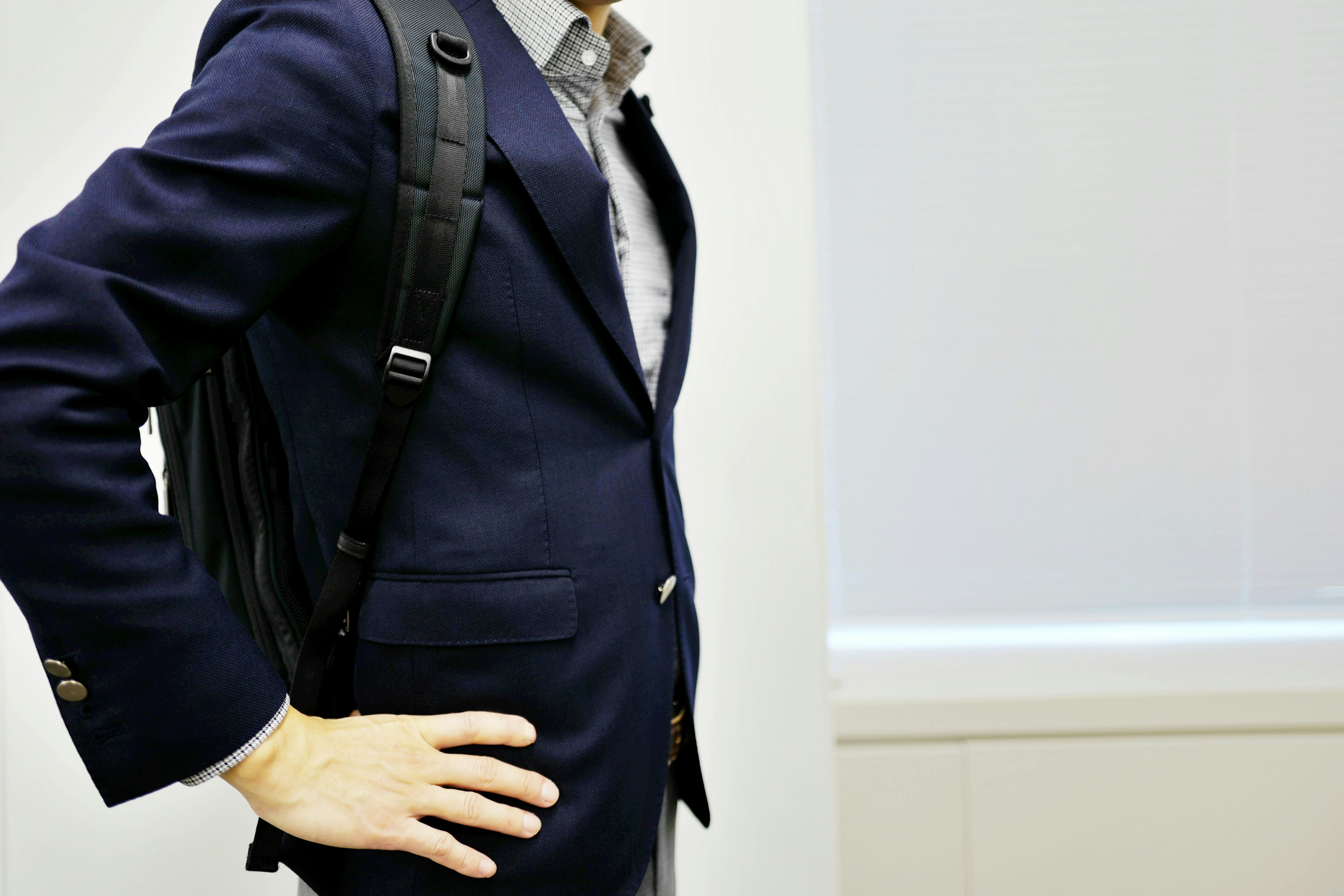 A man in a suit wearing a backpack with a hand on his hip