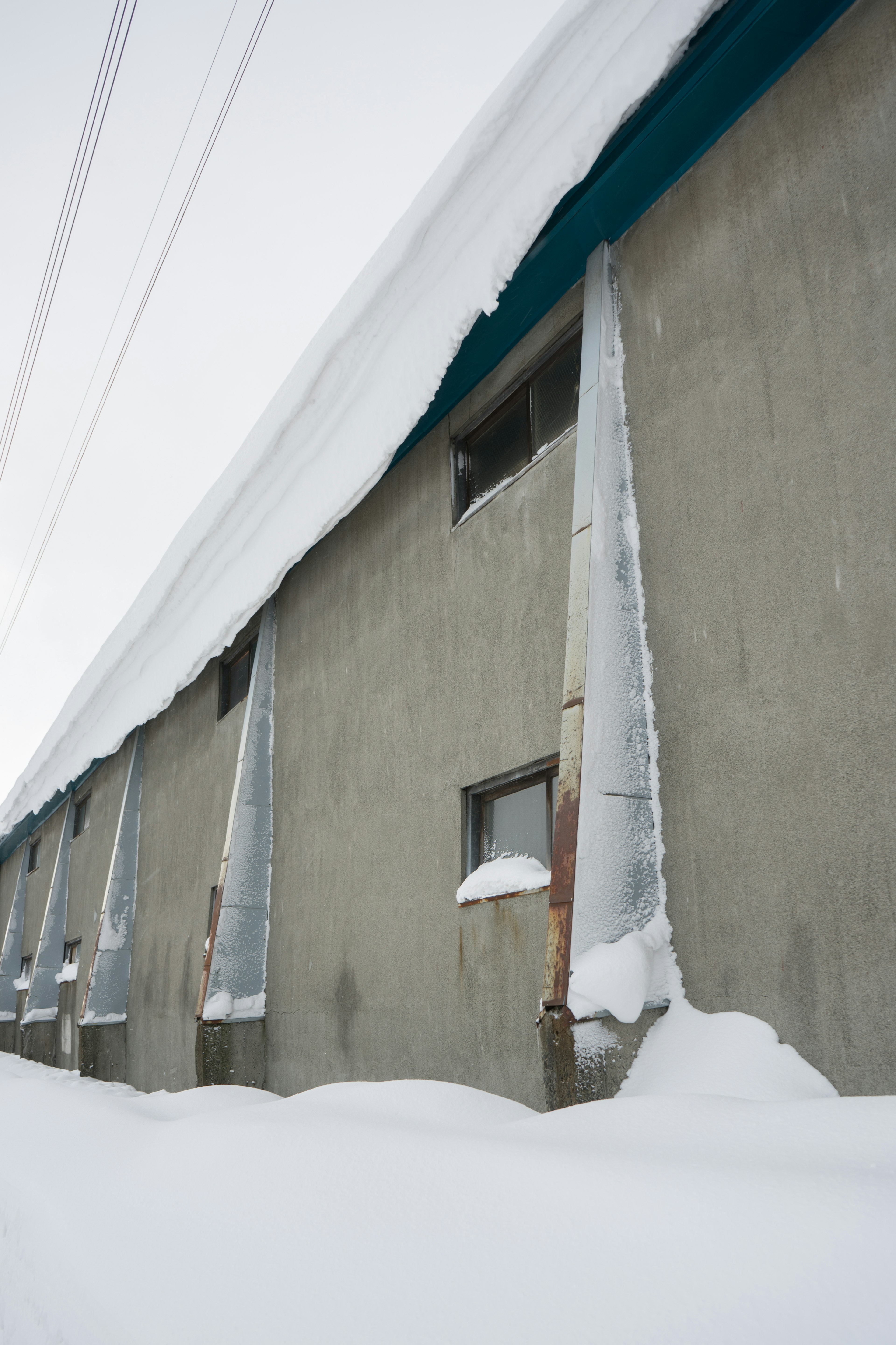 Snow-covered building wall with icicles